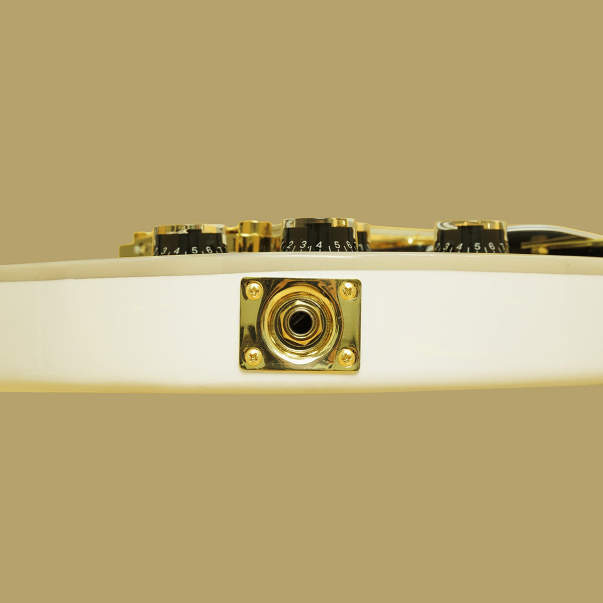 Gold output jack plate on the side of the white Stagg 30th Anniversary Legacy guitar