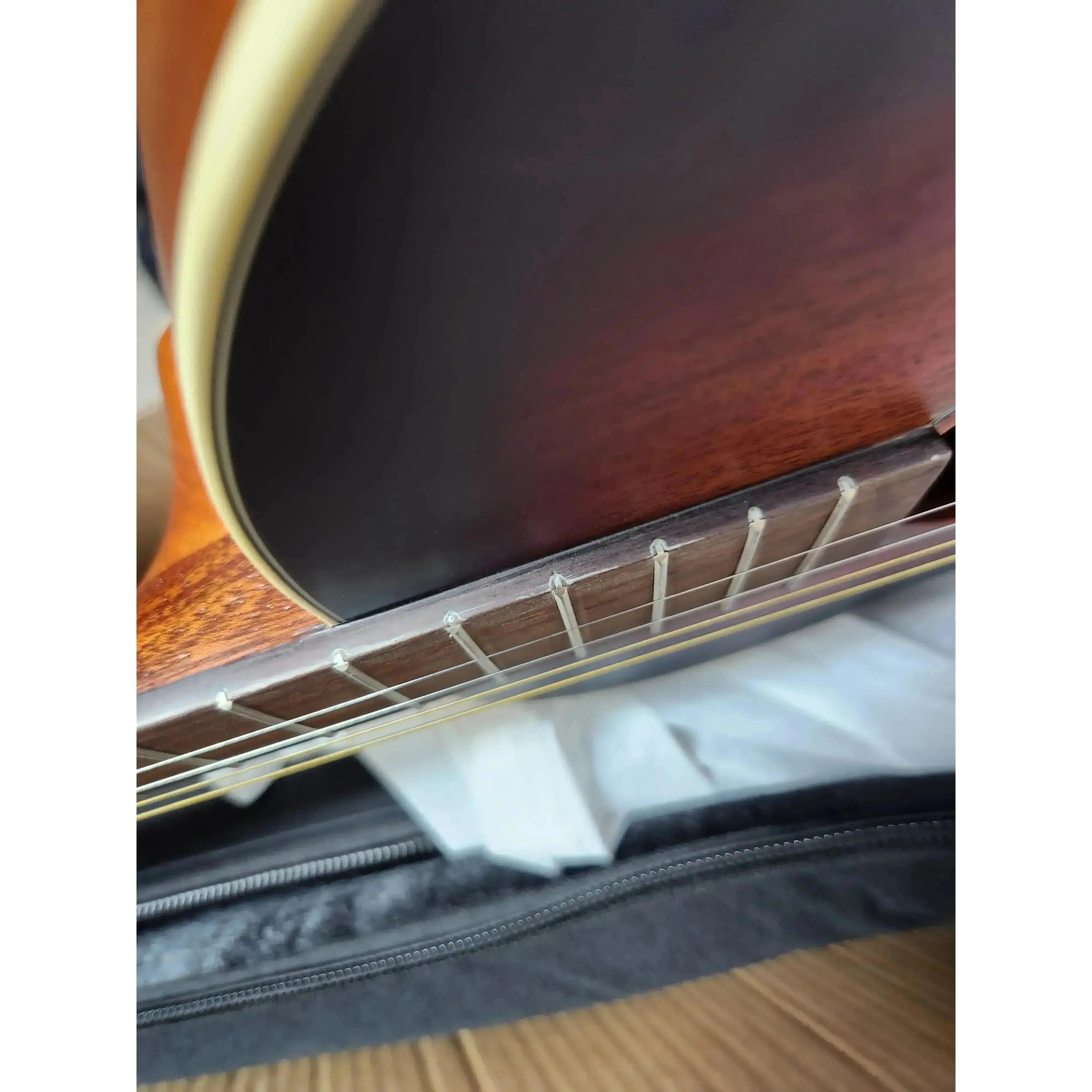 Kala GTR-TB tenor guitar fretboard with chipping, showing sunburst mahogany top and cream binding.