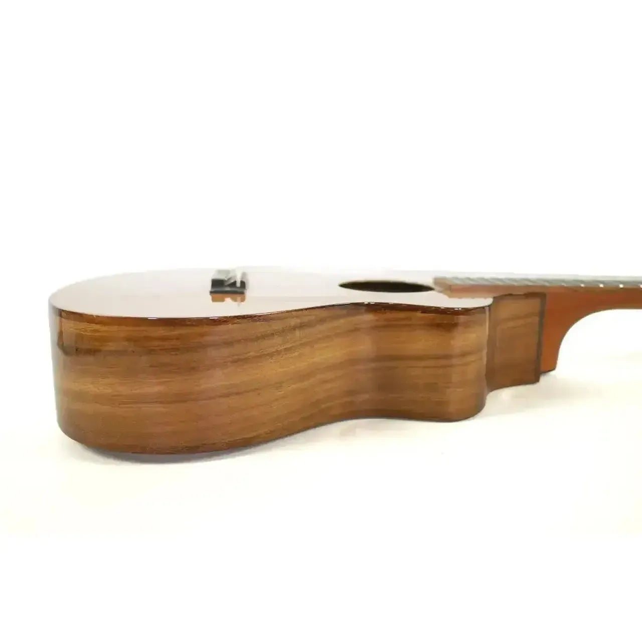 Kala Trembesi Baritone Ukulele, side view, showing glossy brown wood grain and curved body.