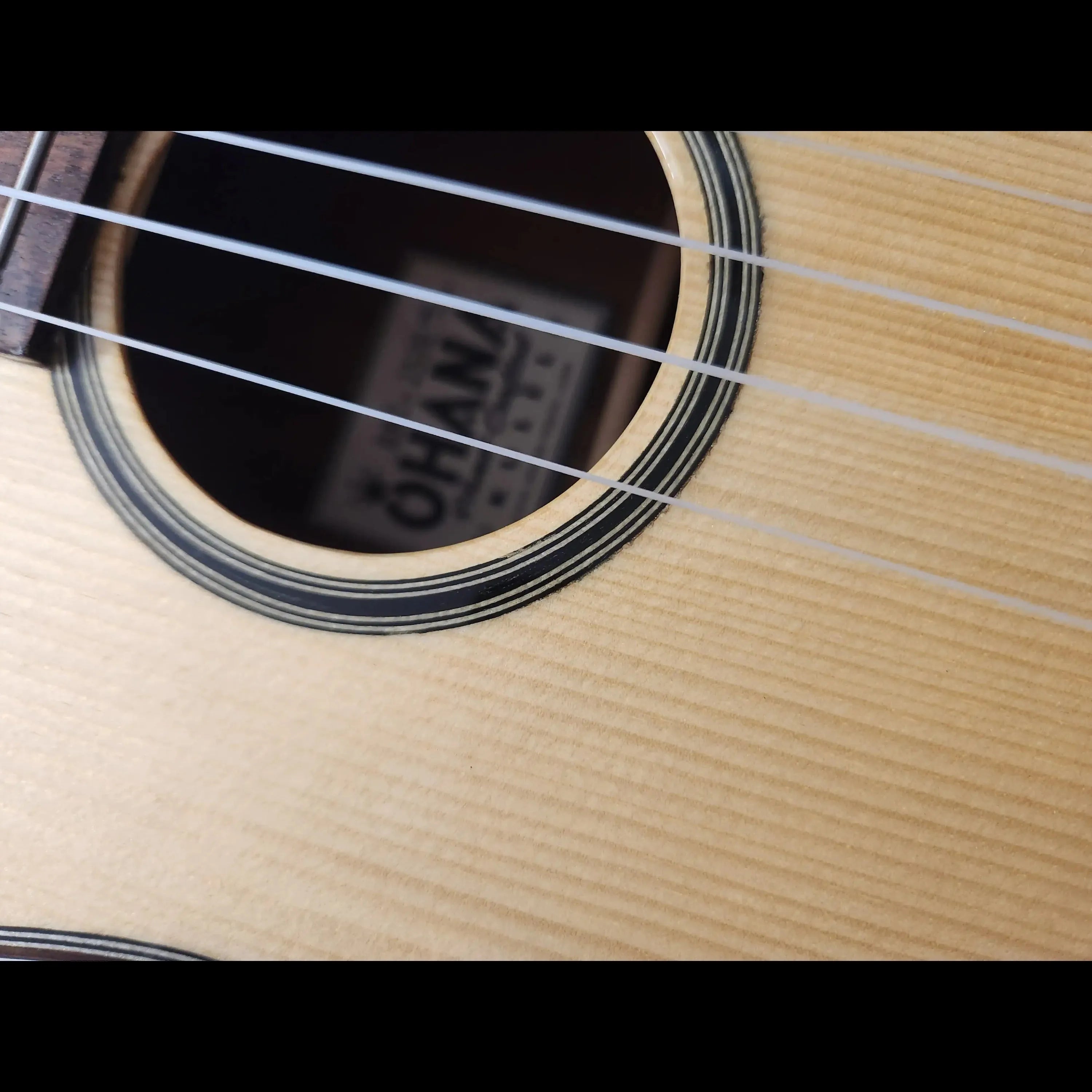 Close-up of Ohana BKT-250G Baritone Ukulele's spruce top, soundhole, and strings.