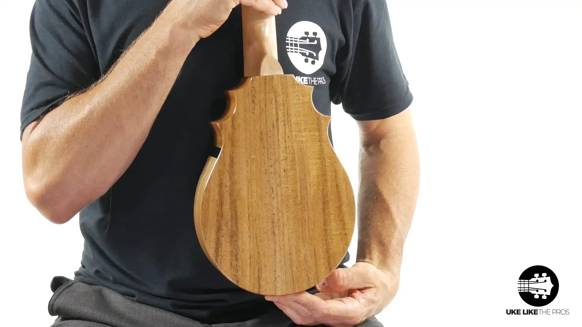 Back view of natural wood ukulele with cutaway, held by person. Terry Carter Music Store.