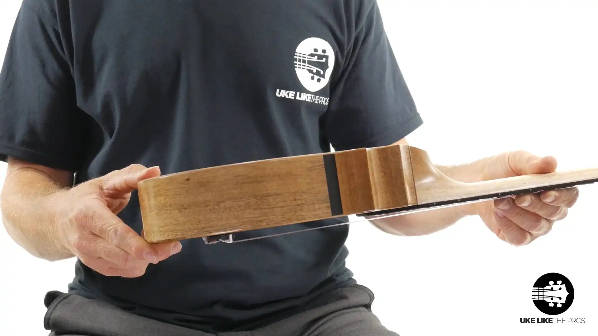 Side view of a natural wood ukulele being held, Terry Carter Music Store product photo.