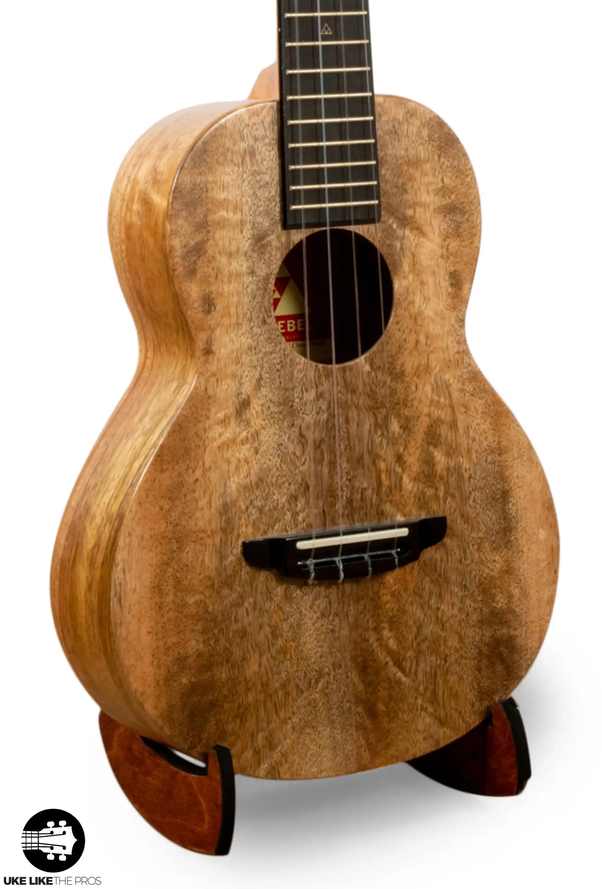 Rebel ukulele with natural figured wood body on stand at Terry Carter Music Store