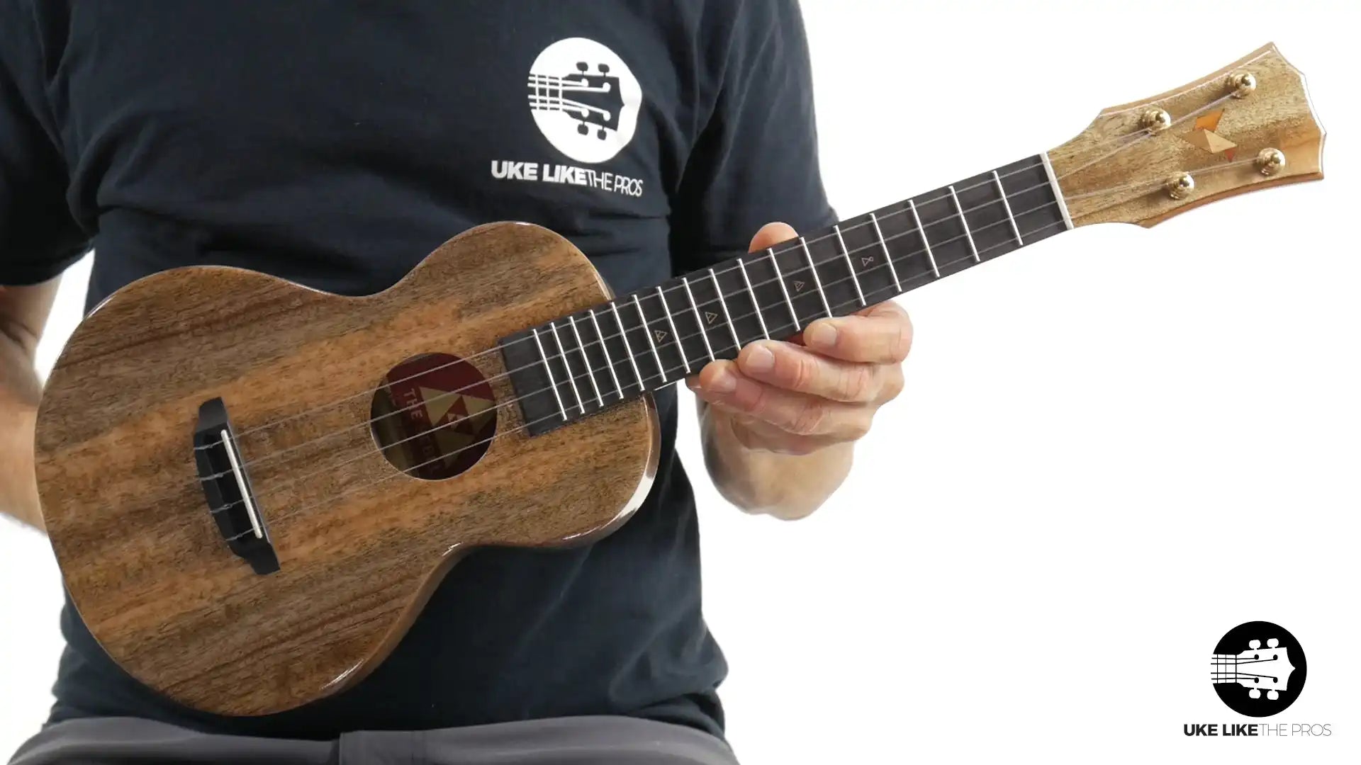 Rebel ukulele with natural wood finish held by player, Terry Carter Music Store