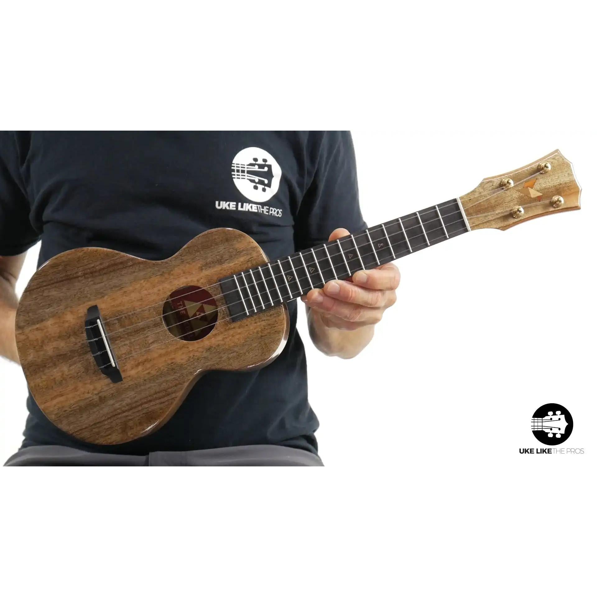Rebel ukulele with natural wood finish held by player, Terry Carter Music Store