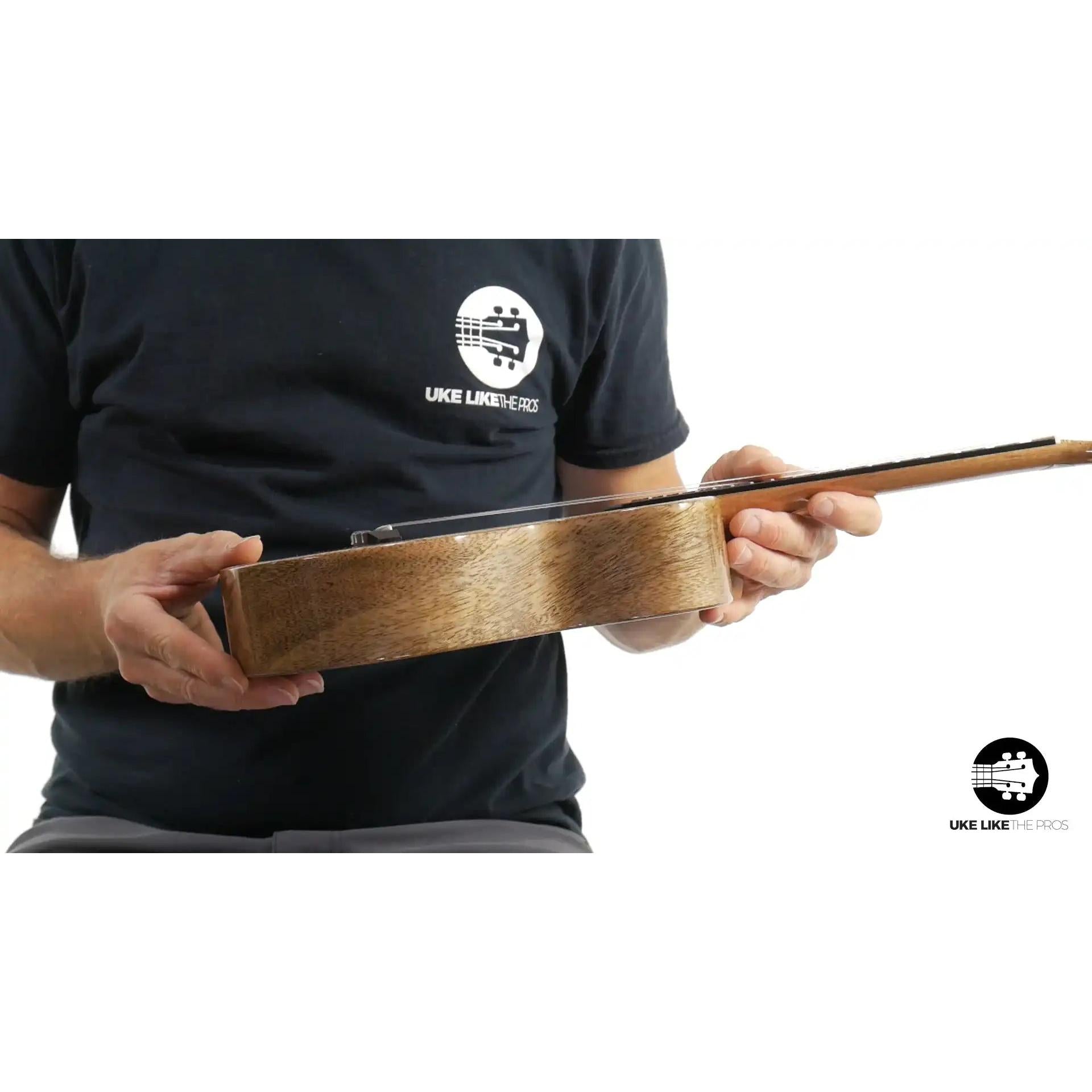 Romero Creations ukulele with natural wood grain side view, held by person, Terry Carter Music Store