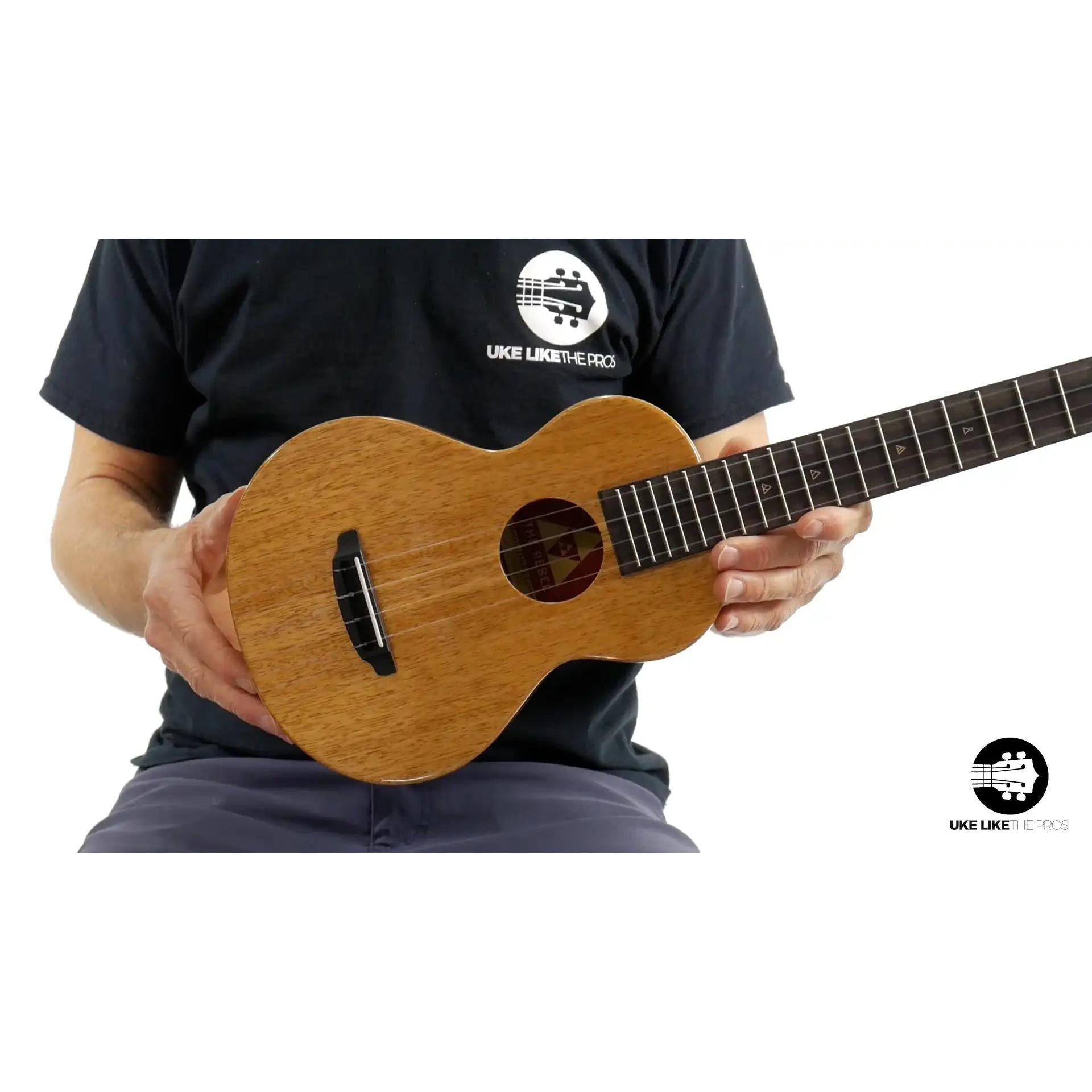 Rebel Double Creme Concert mahogany ukulele at Terry Carter Music Store, shown held, wood grain visible.