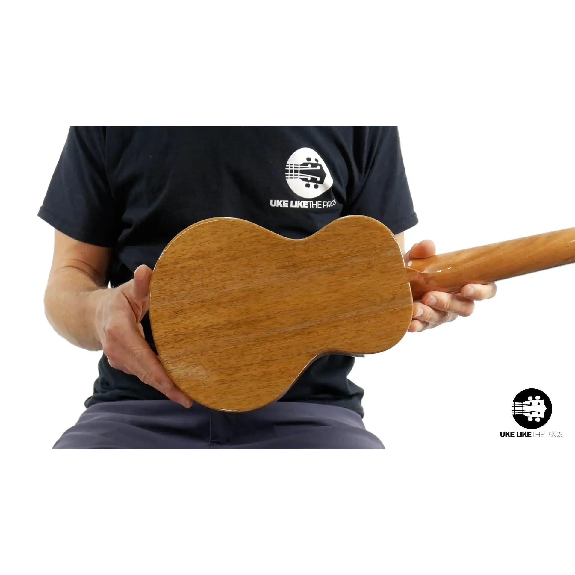 Back view of wooden ukulele held by person, natural finish, Terry Carter Music Store product photo.