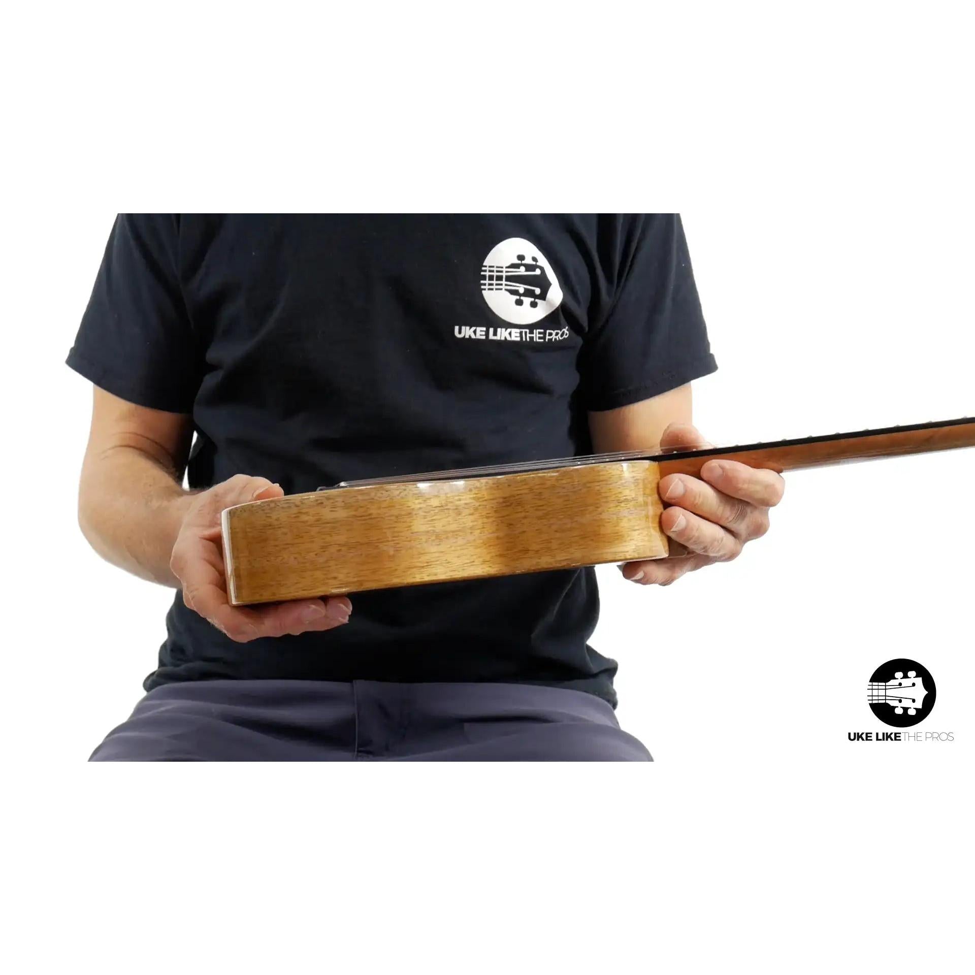 Side view of Rebel ukulele with natural wood body, held by person, Terry Carter Music Store