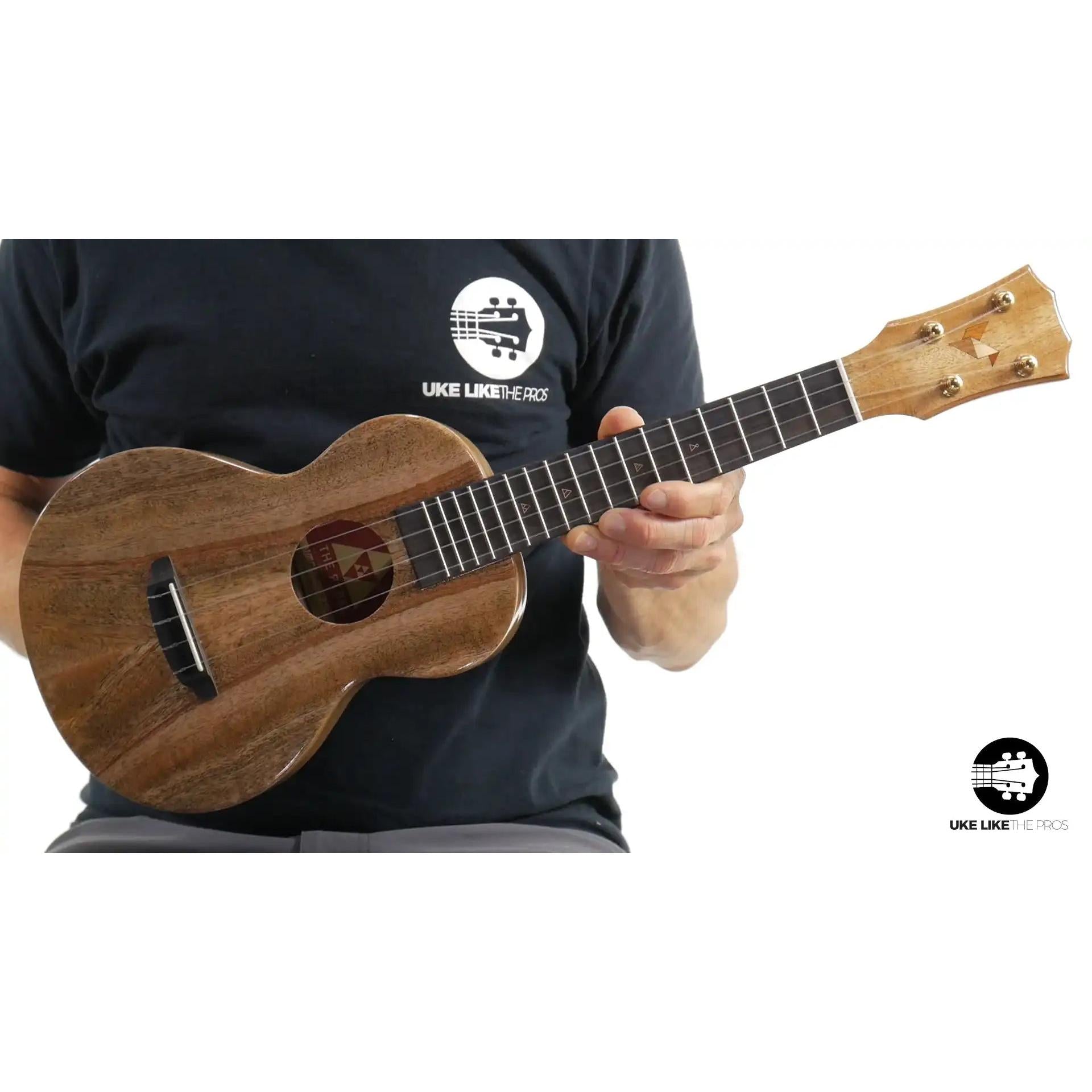 Rebel Double Creme Concert ukulele with natural wood grain held by player, Terry Carter Music Store