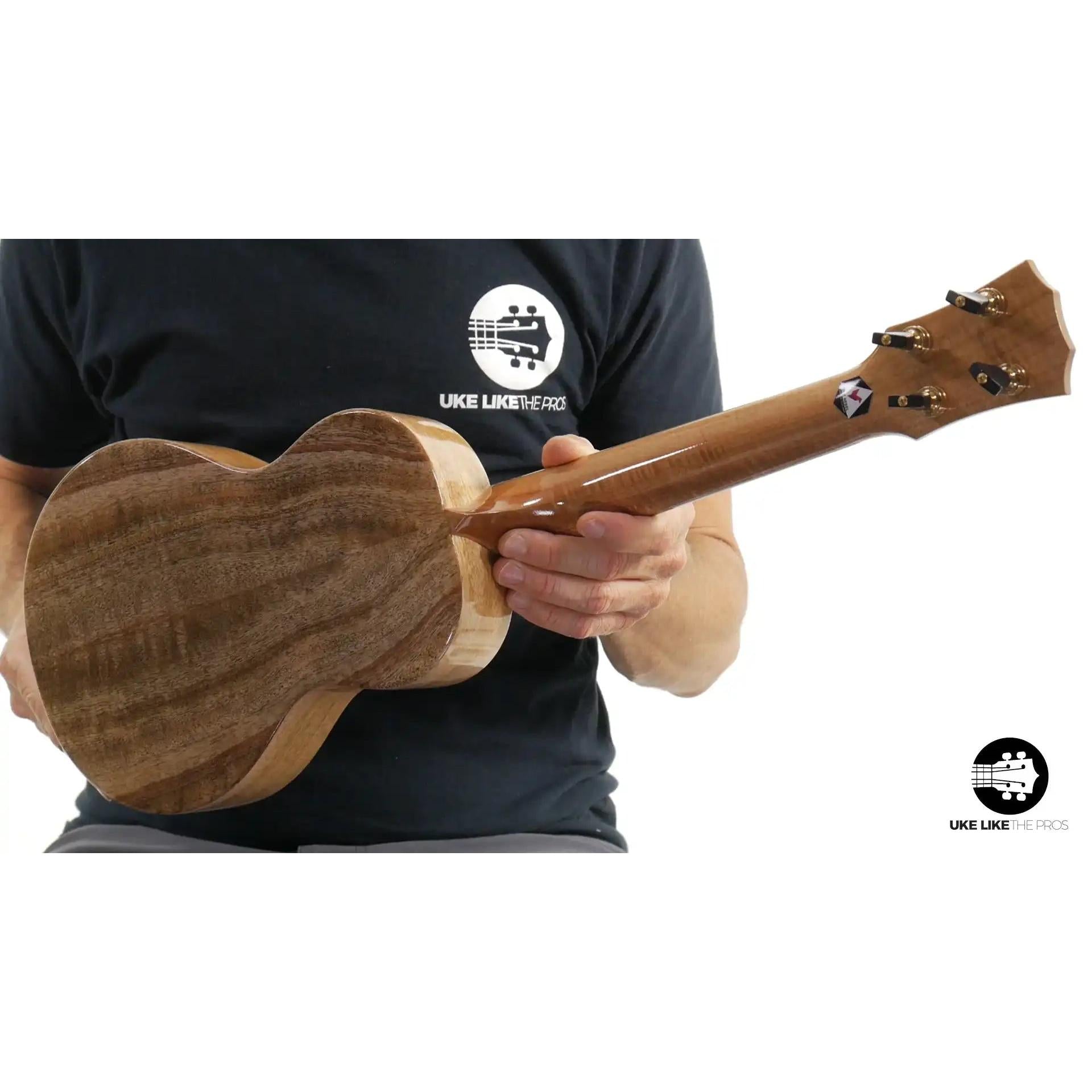 Back of Rebel ukulele with natural wood grain, held by person, Terry Carter Music Store
