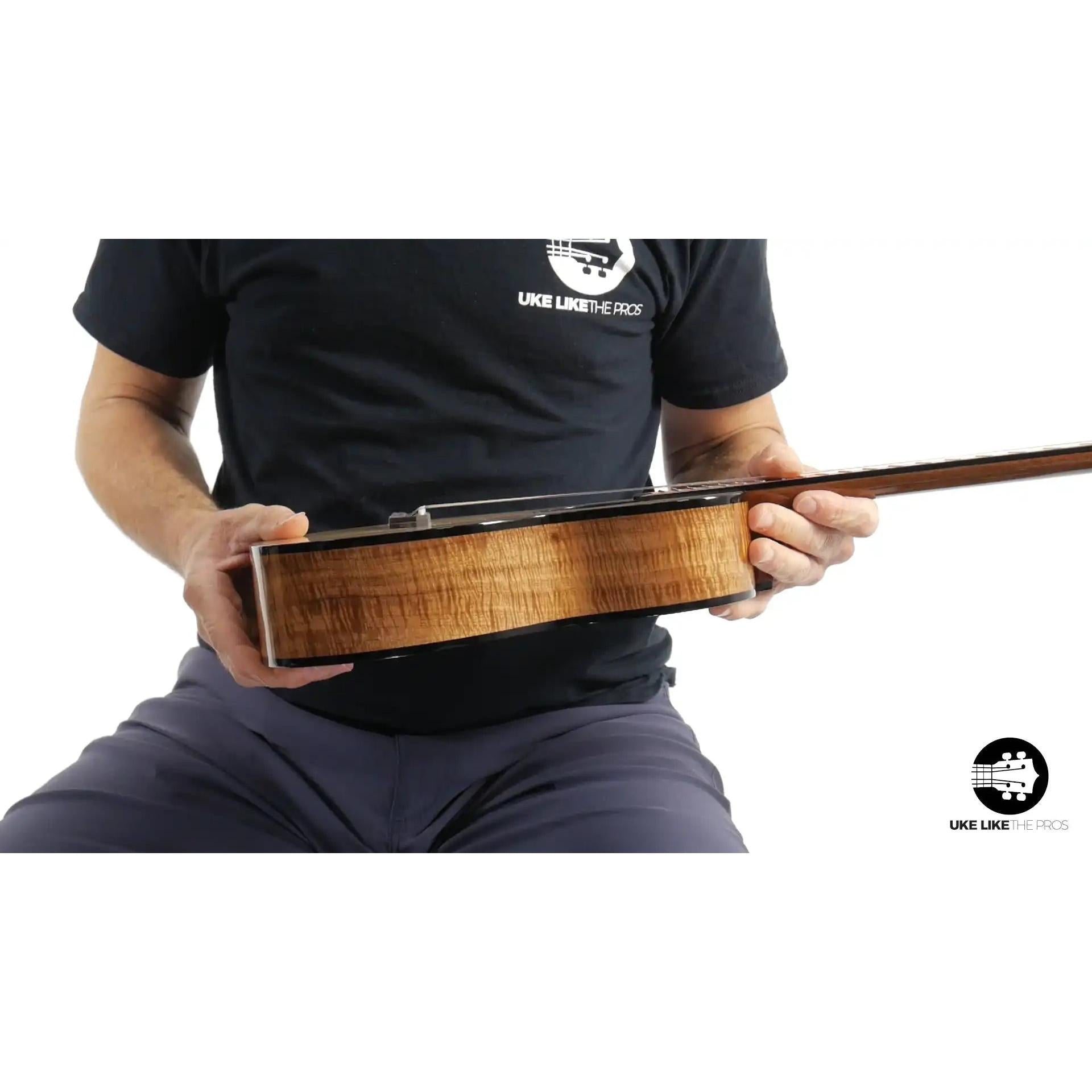 Side view of Rebel ukulele with figured wood body, held by a person, Terry Carter Music Store