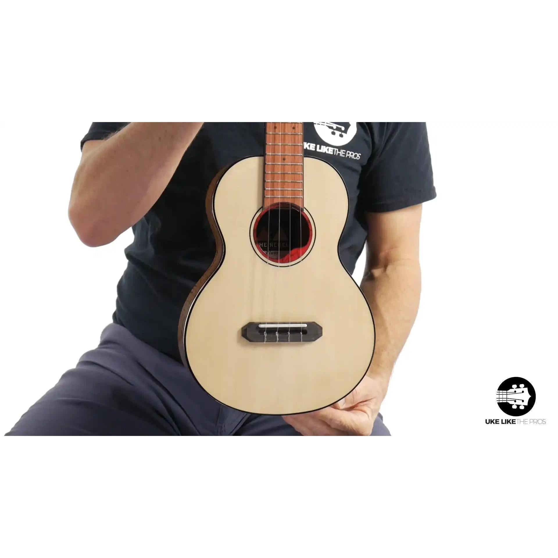 Rebel Pluto ukulele with light wood top held by person, Terry Carter Music Store