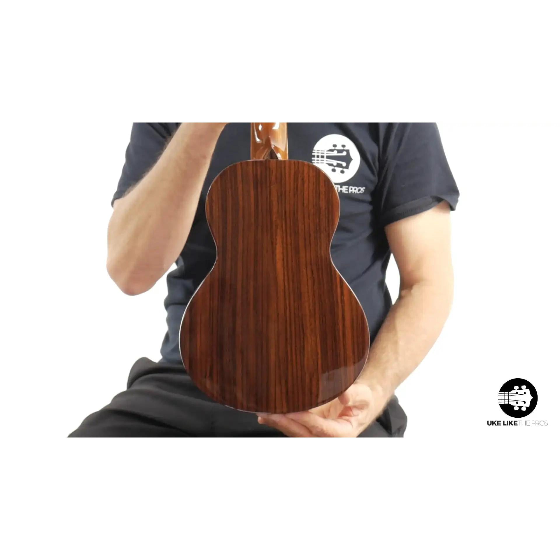 Glossy dark wood ukulele back, Rebel brand, held by person. Terry Carter Music Store.