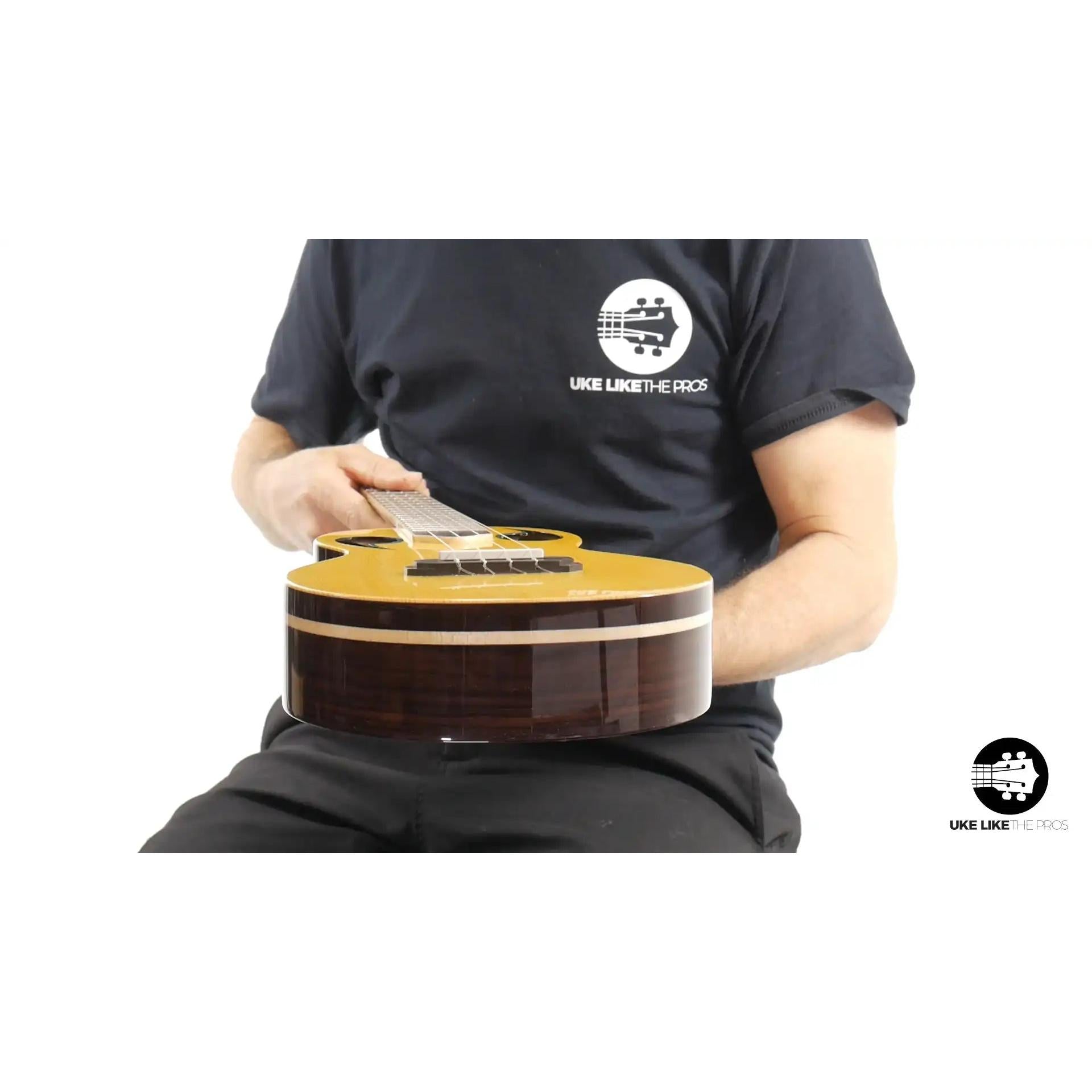 Person holding a Rebel Quark ukulele with natural wood top and dark wood sides at Terry Carter Music Store