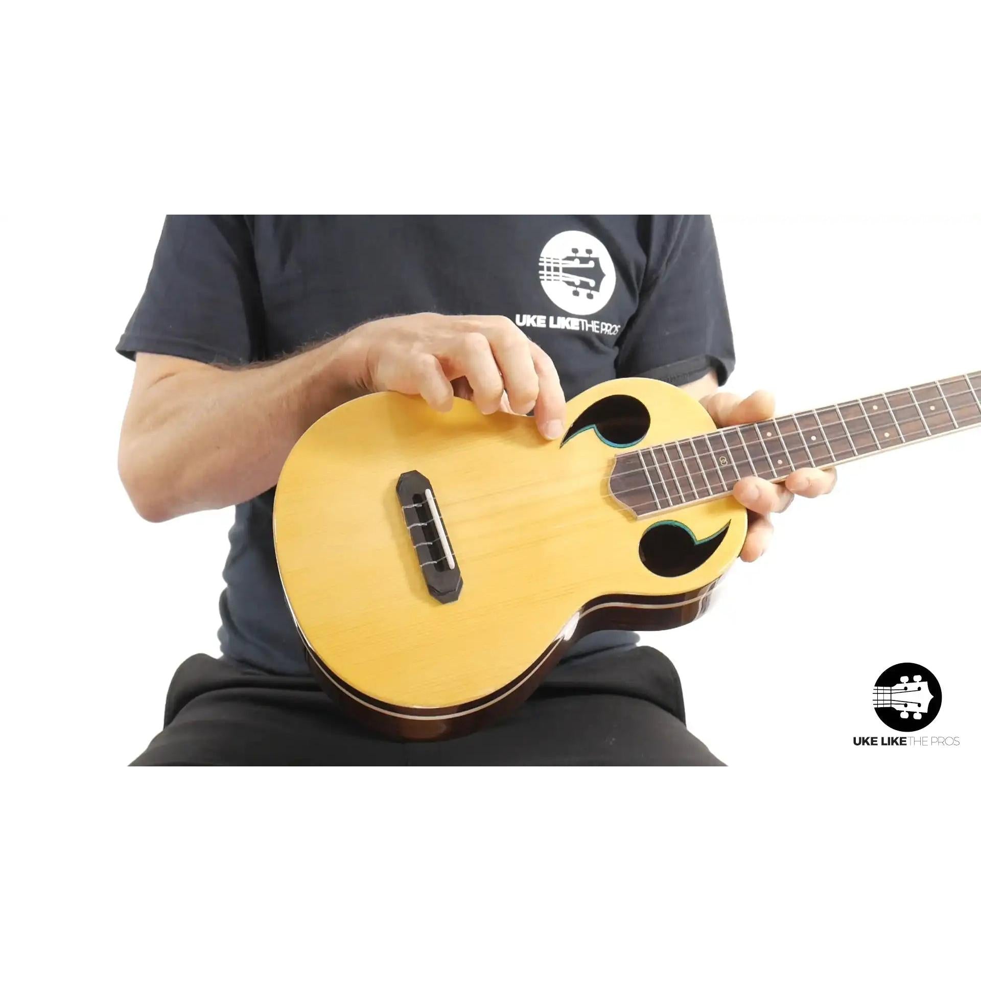 Person holding Rebel Quark Hitman B ukulele with natural wood top at Terry Carter Music Store