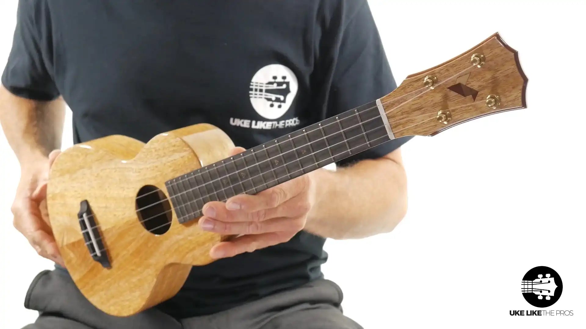 Glossy wood ukulele with unique headstock in hand, natural finish, Terry Carter Music Store