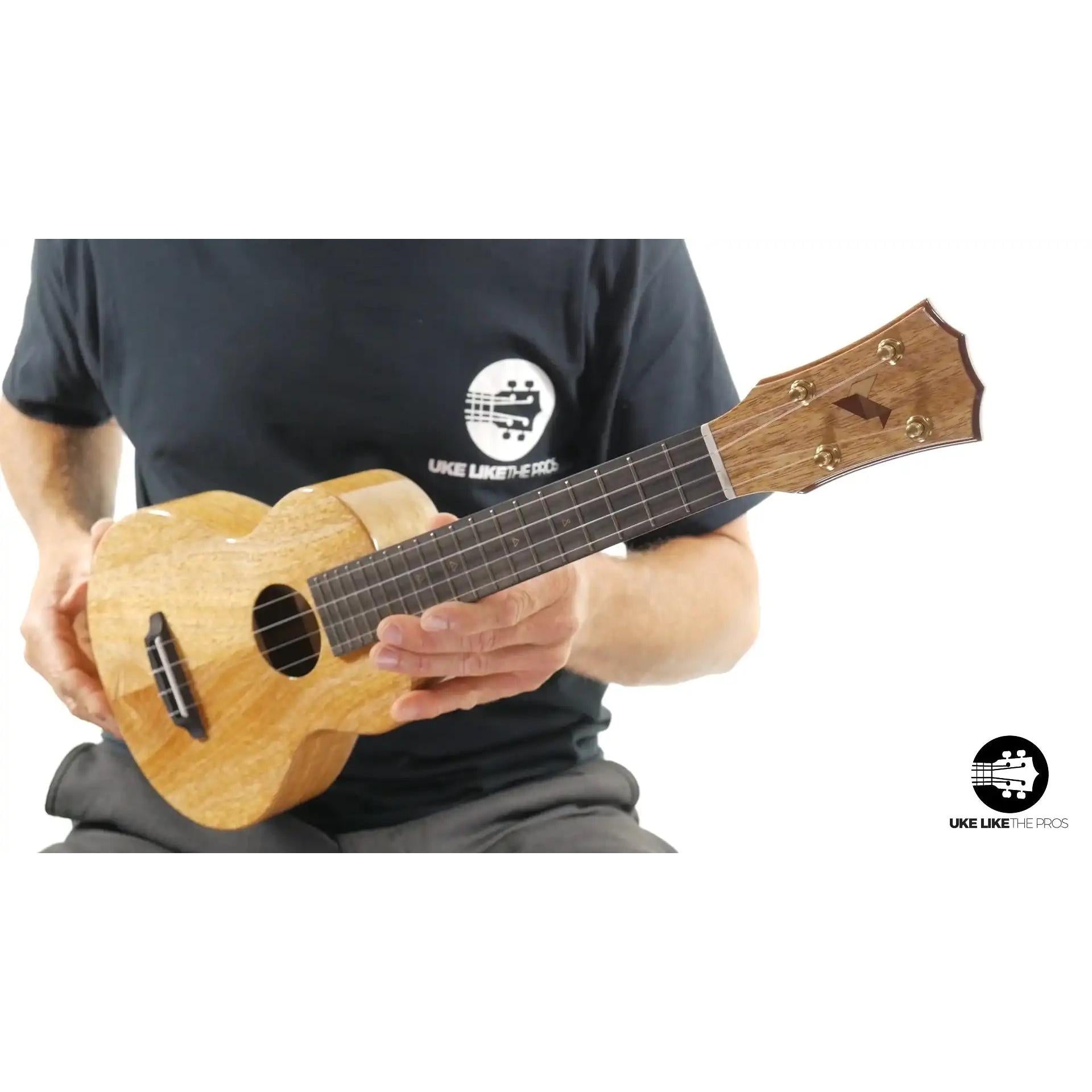 Glossy wood ukulele with unique headstock in hand, natural finish, Terry Carter Music Store