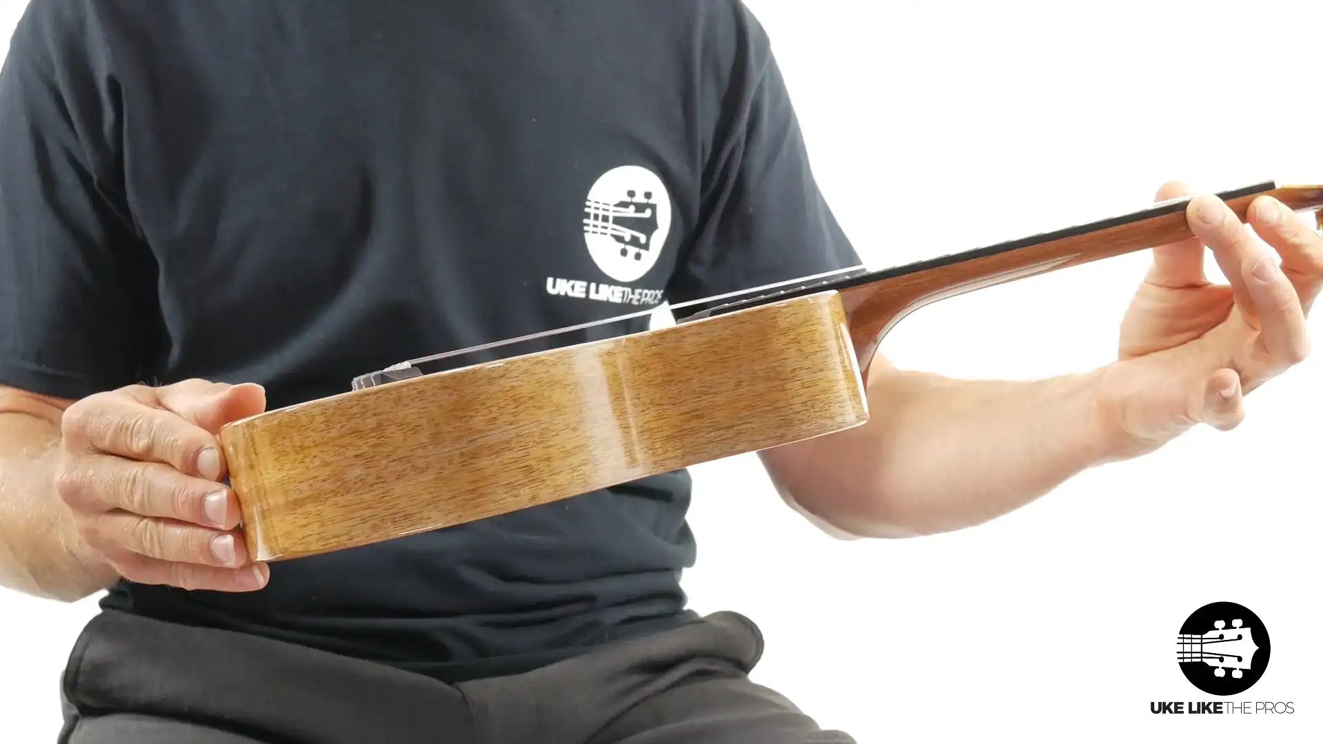 Side view of a natural wood ukulele held by a person, available at Terry Carter Music Store