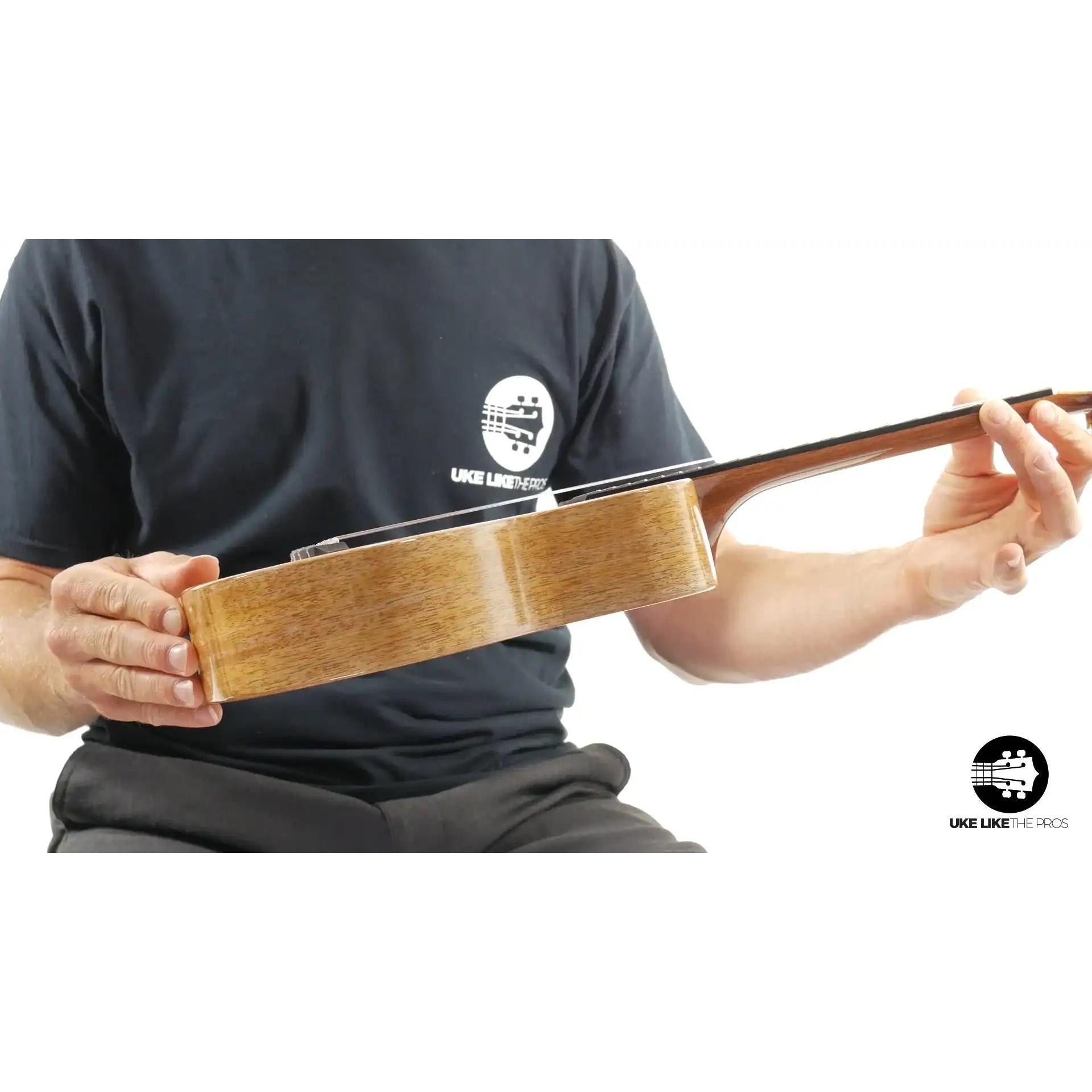 Side view of a natural wood ukulele held by a person, available at Terry Carter Music Store
