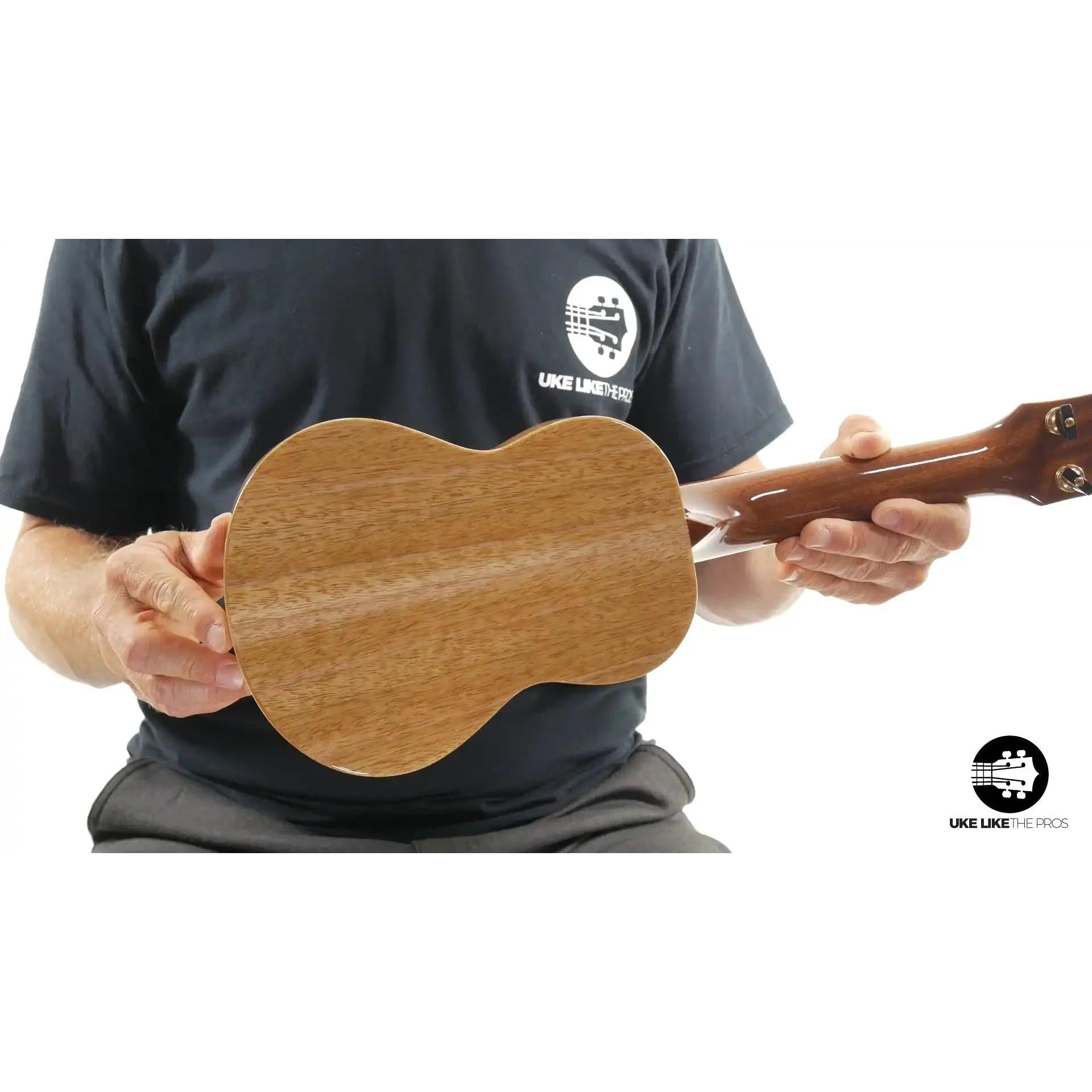 Person holding a Little Giant ukulele with natural wood back at Terry Carter Music Store.