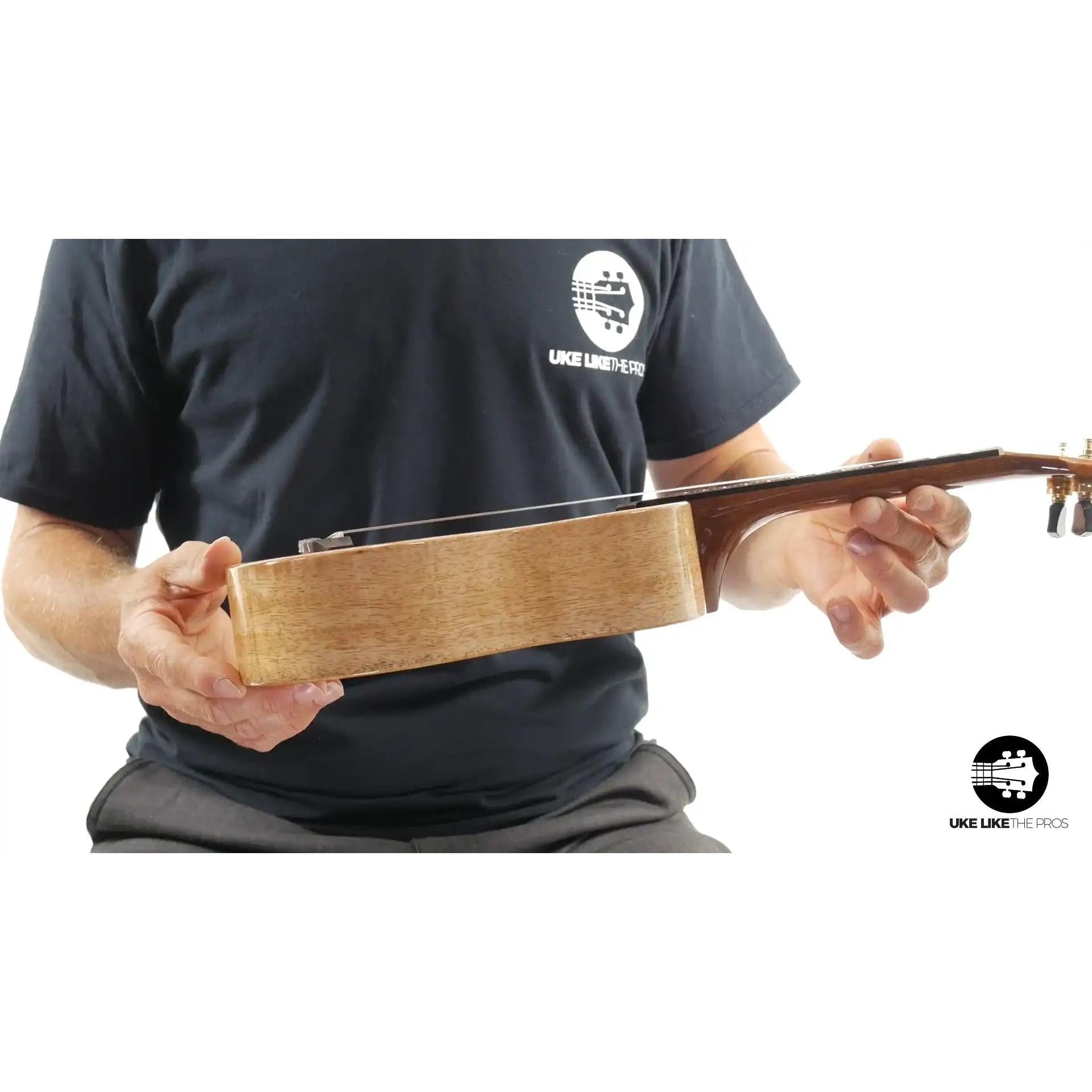 Side view of Little Giant ukulele with natural wood body held by person, Terry Carter Music Store