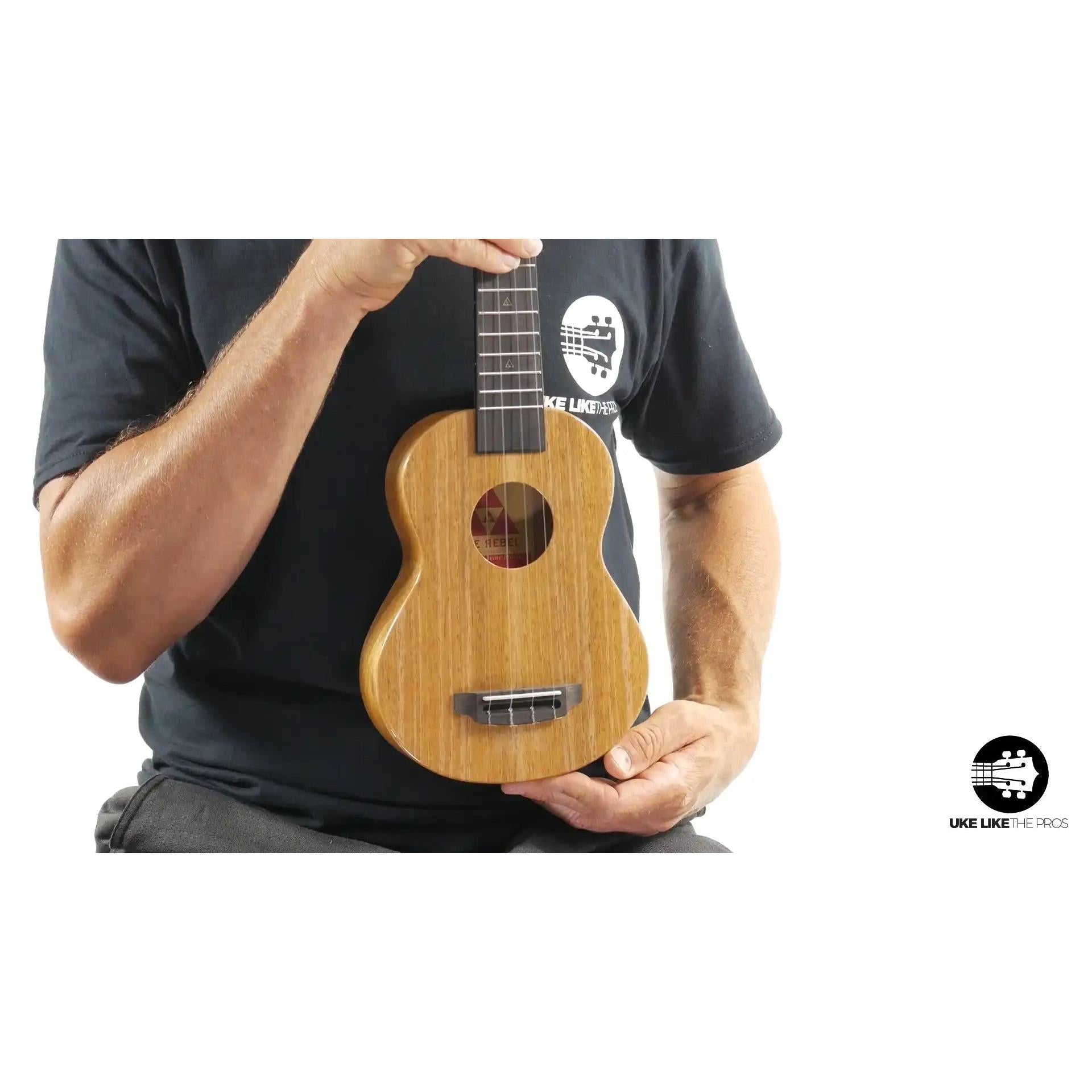 Rebel Mini T-Rex natural wood ukulele held by person, Terry Carter Music Store product photo.