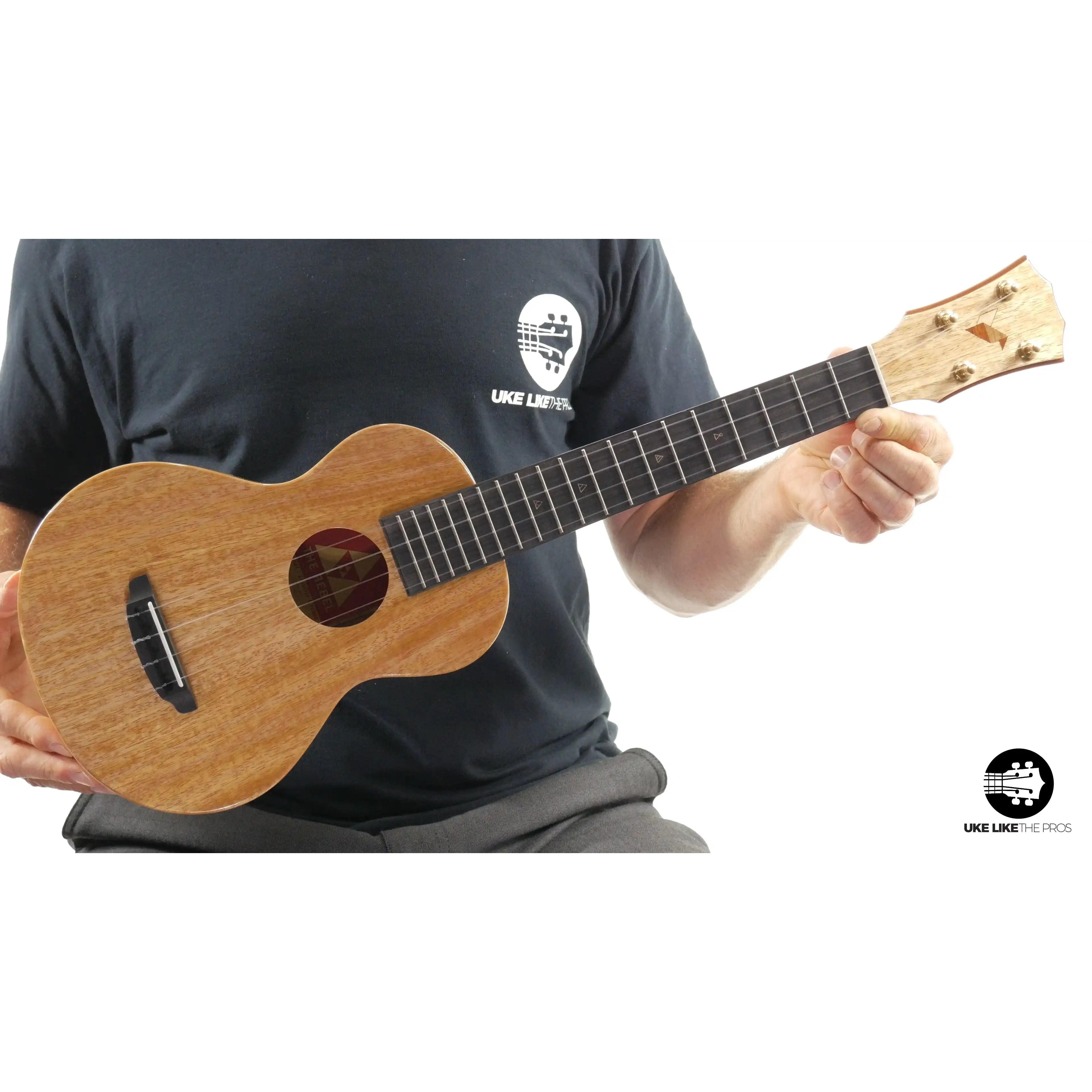 Romero Creations Rebel Double Creme natural wood ukulele held by a person, Terry Carter Music Store