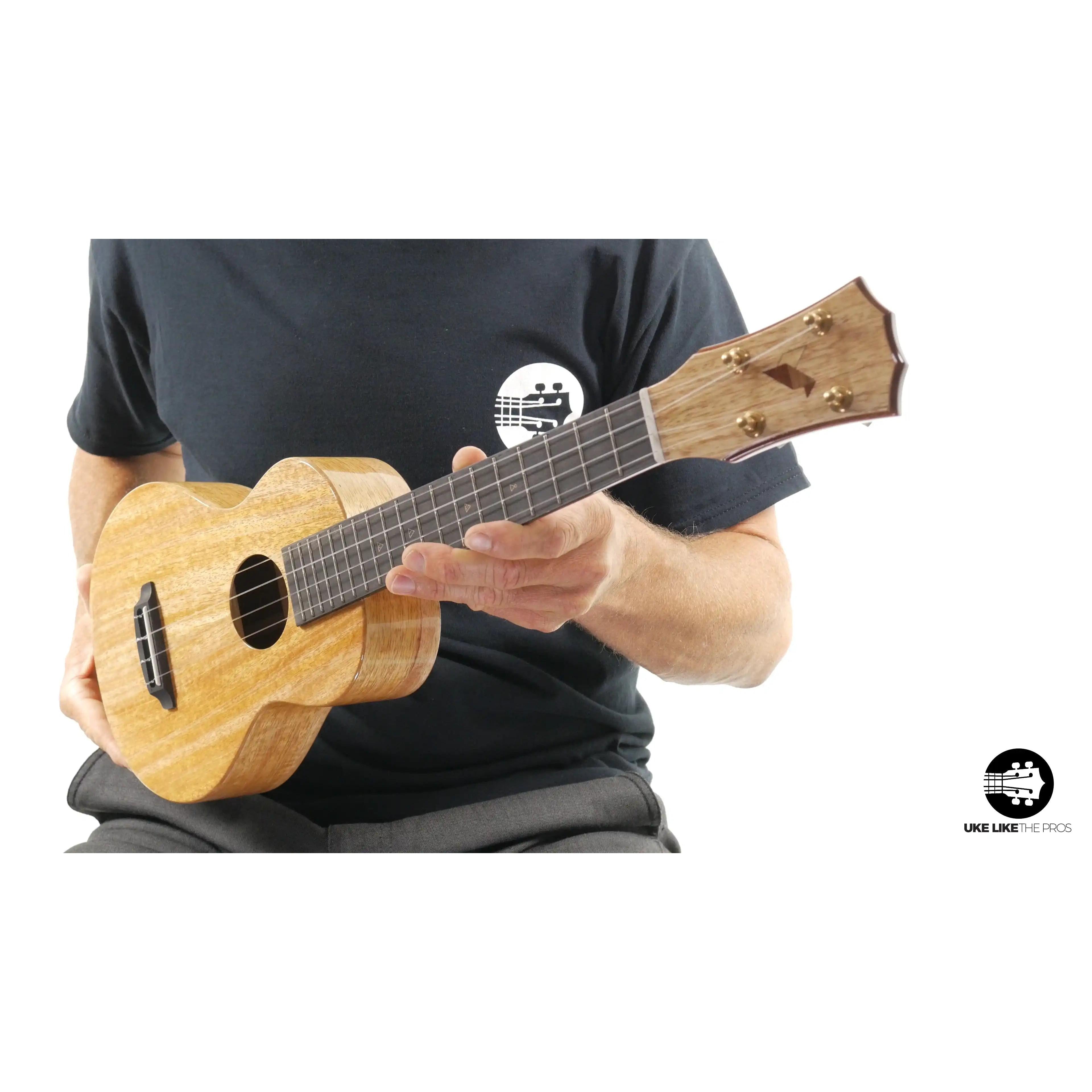 Romero Creations Rebel Double Creme ukulele with natural wood finish held by person, Terry Carter Music Store