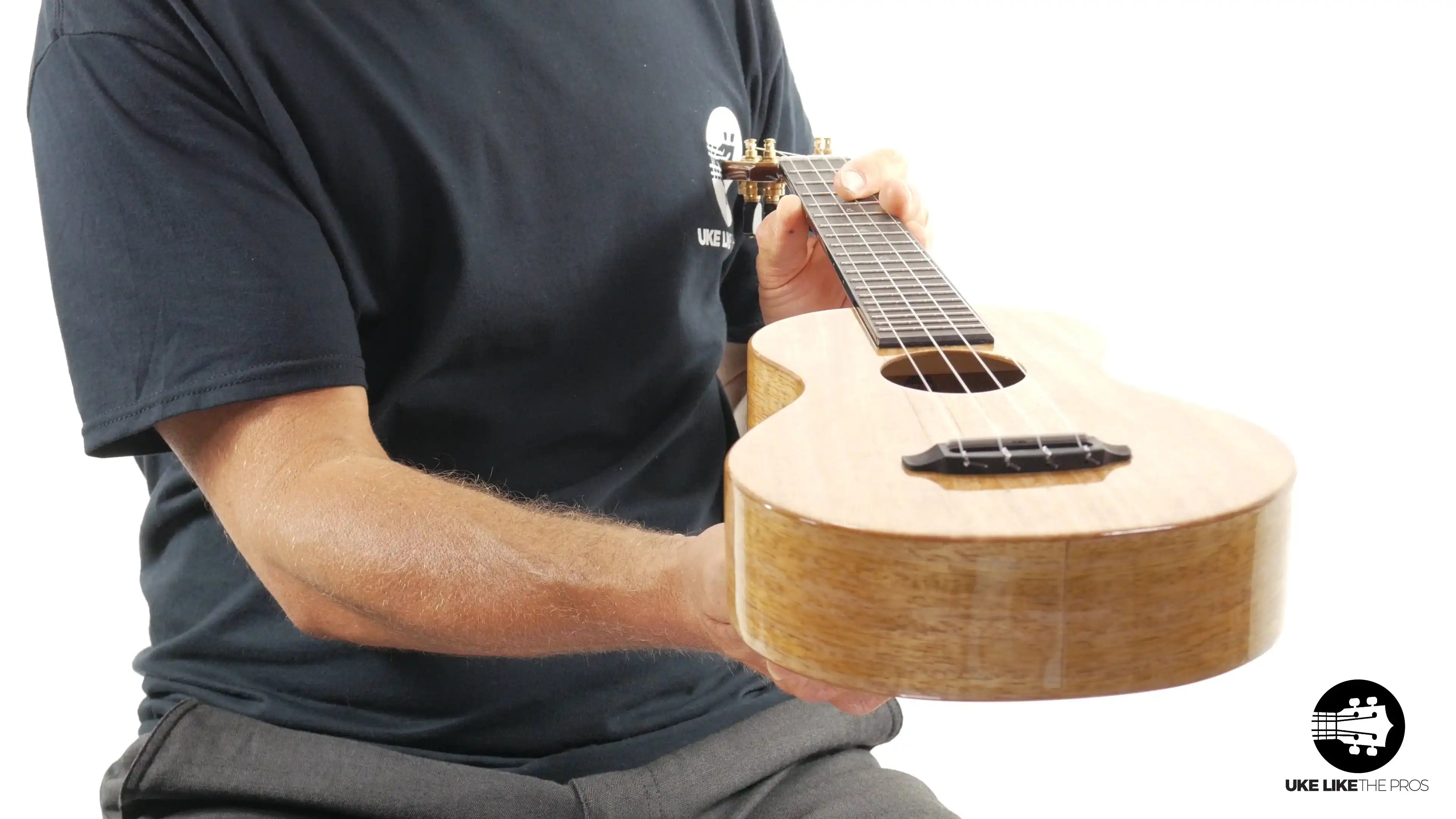 Person holding light wood ukulele with gloss finish, featured at Terry Carter Music Store.