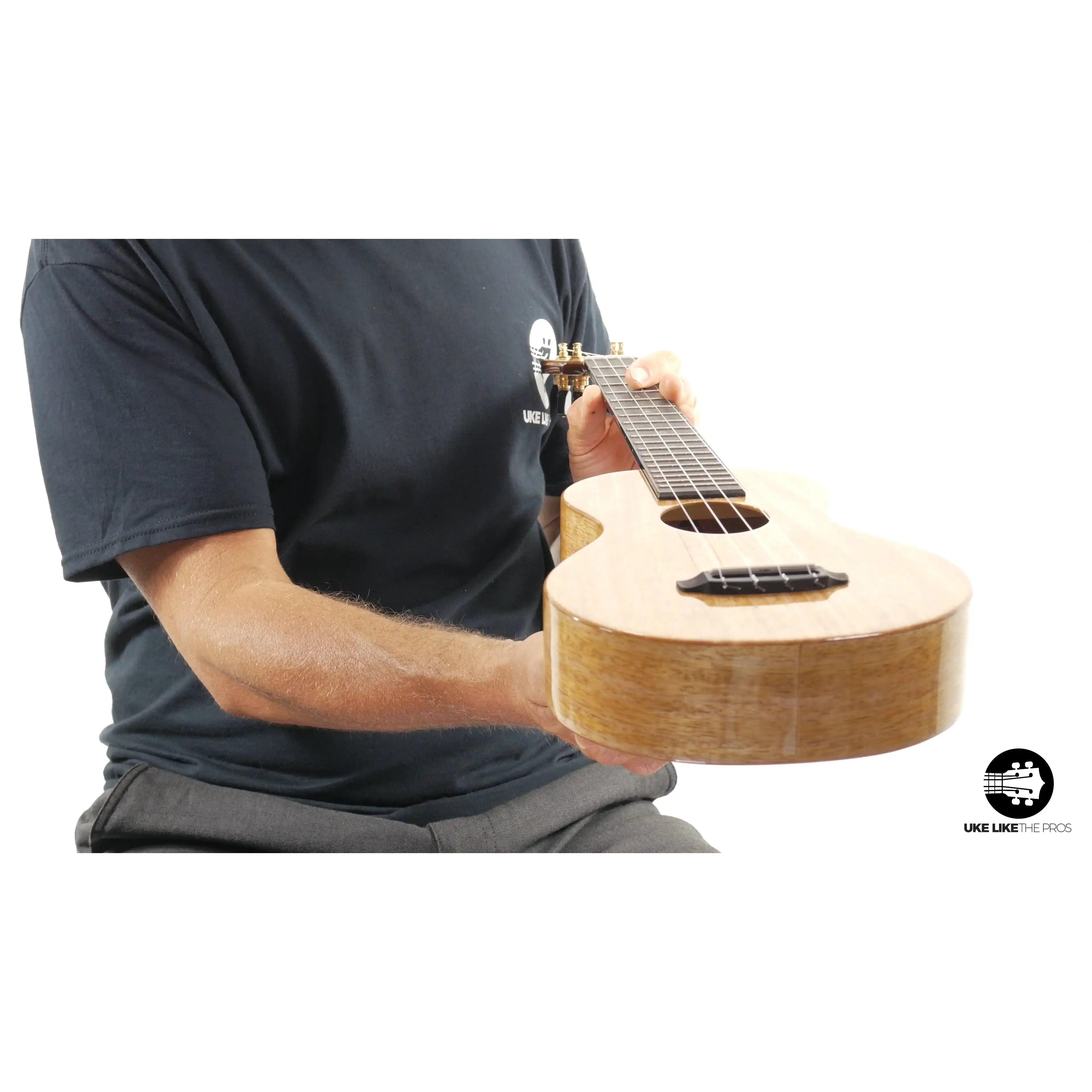 Person holding light wood ukulele with gloss finish, featured at Terry Carter Music Store.