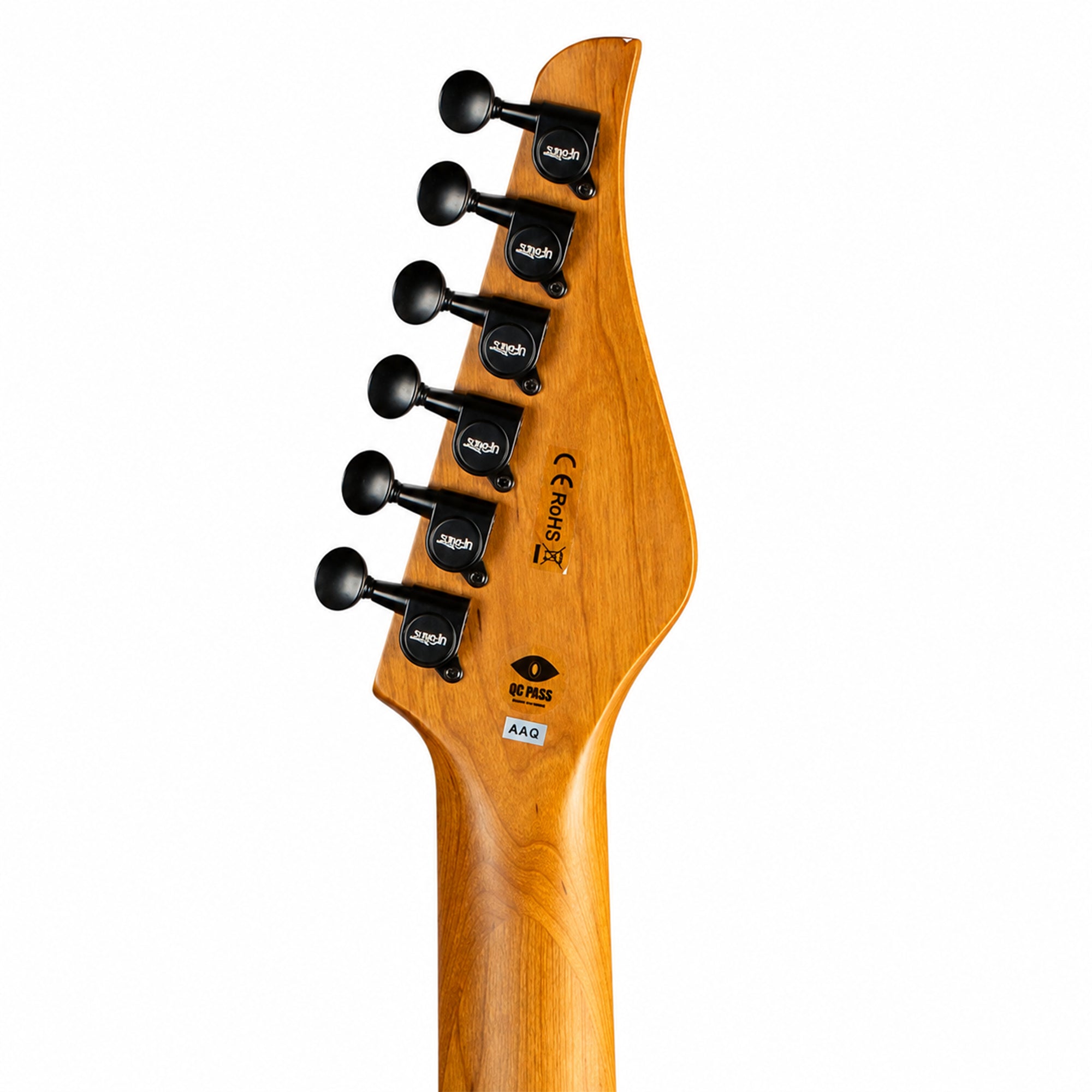 Close-up of the headstock of an electric guitar, showing a warm honey-amber wood finish, black tuning pegs labeled 'Jaguar', and branding stickers including 'Shope' and 'AAG' on a plain white background.