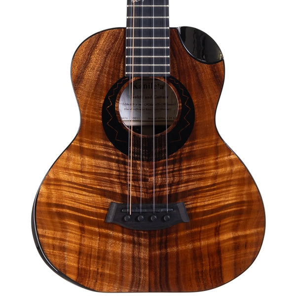 A close-up studio shot of a Kanile'a Willie`K 5-String Super Tenor Ukulele body with a rich, figured wood grain finish in warm brown and amber tones, featuring a black soundhole rosette, bridge, and tailpiece, and part of the dark fretboard visible at the top.