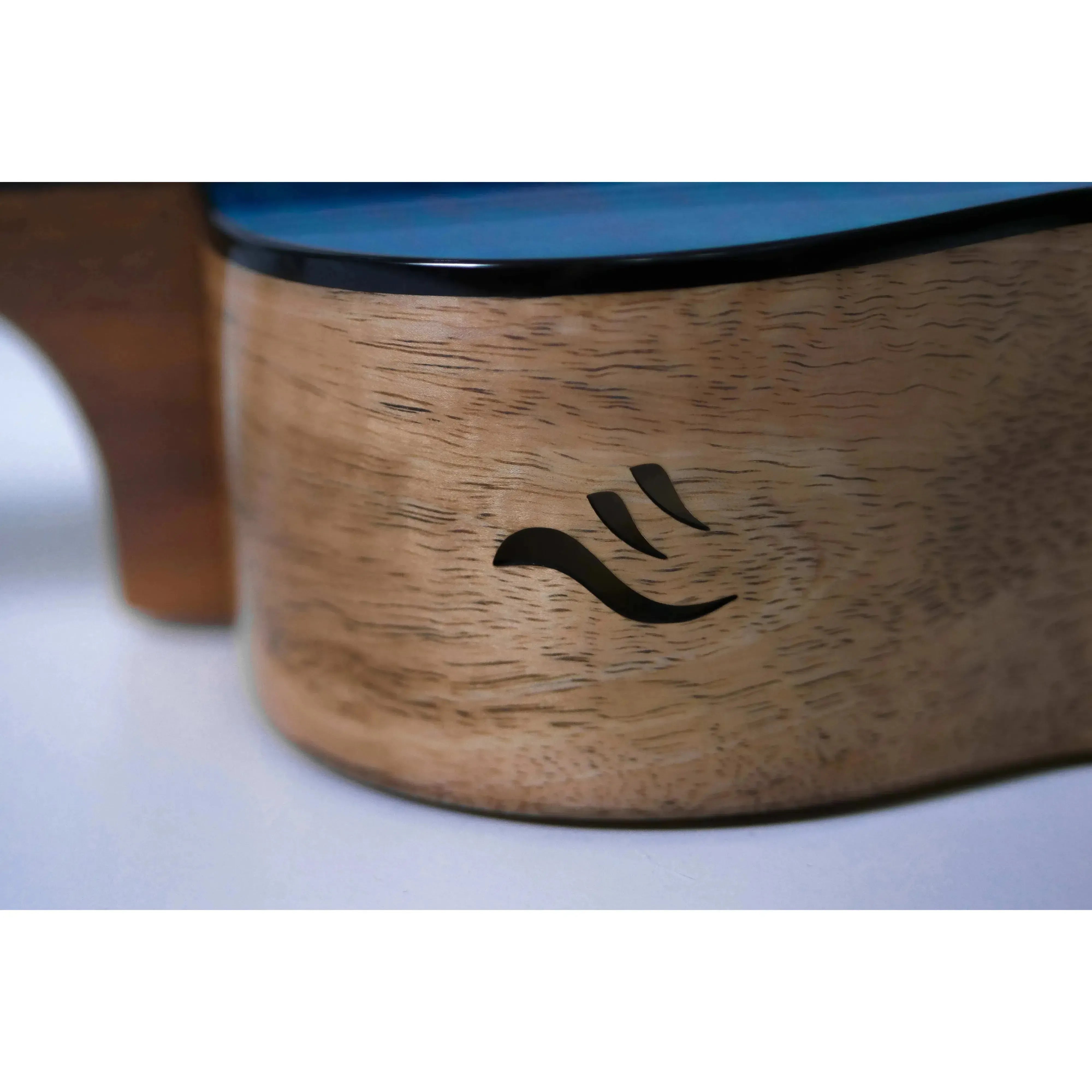 Close-up of Flight Comet Blue Tenor Ukulele's light wood body with black wave logo and blue top.
