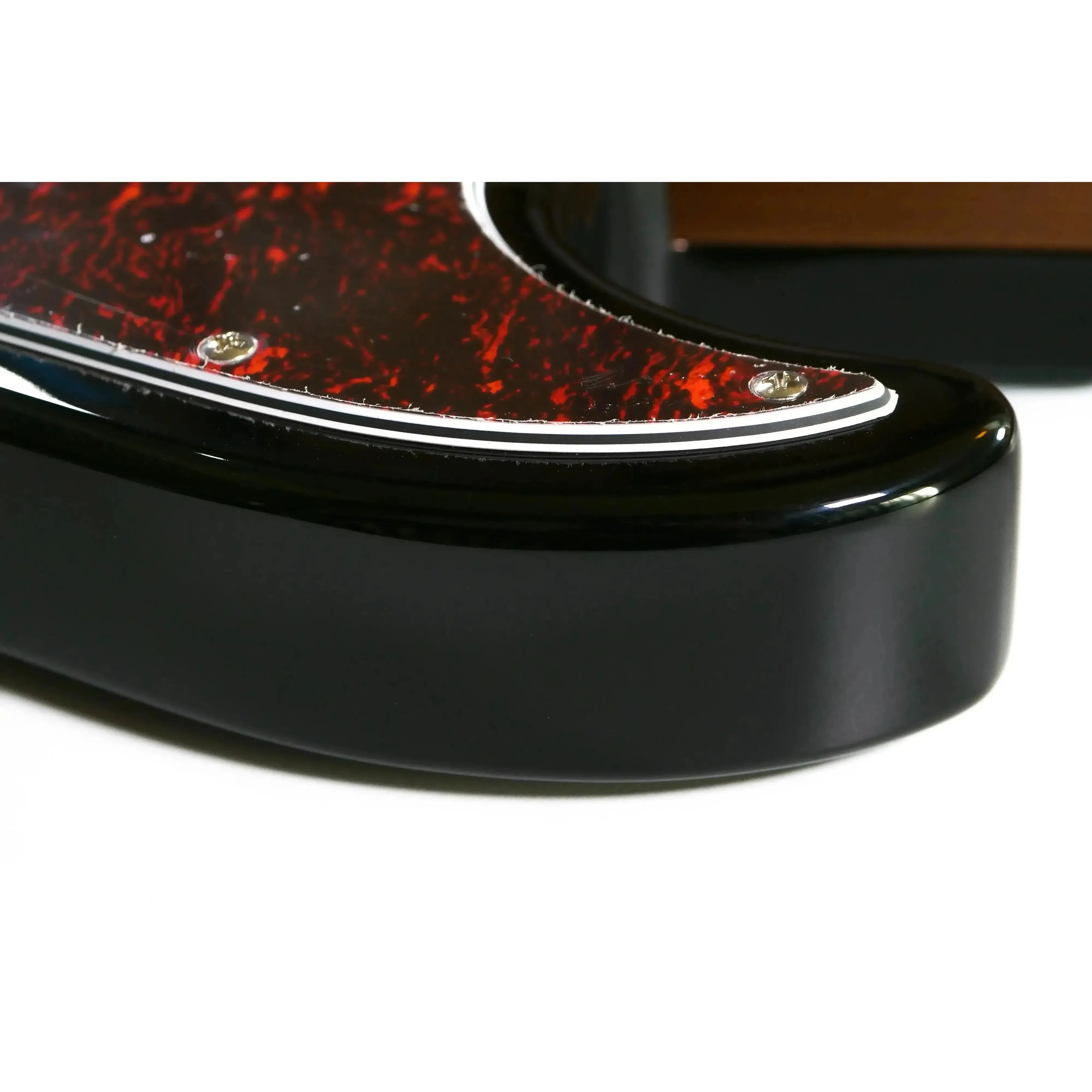 Close-up of Flight JB SB Electric Mini Bass body, showing glossy black finish and tortoiseshell pickguard.