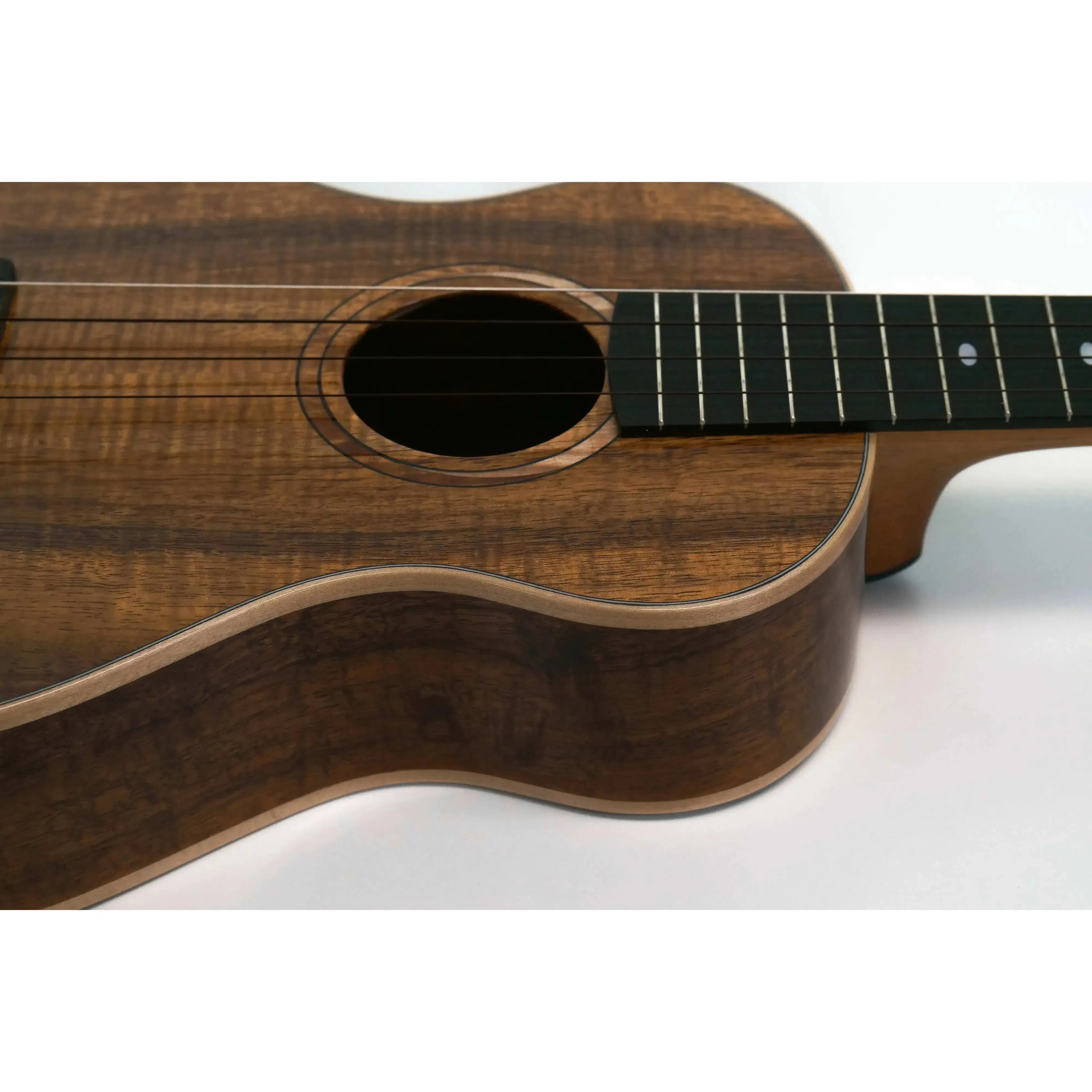 Kala Elite KOA-STG Solid Koa Super Tenor XL Ukulele body with dark wood grain, soundhole, and fretboard.