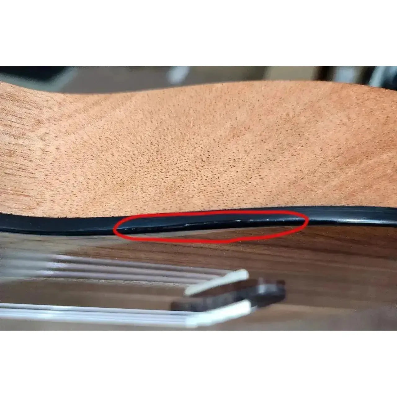 Close-up of Kala Revelator Night Owl Acacia Tenor Ukulele side, showing discoloration under finish.
