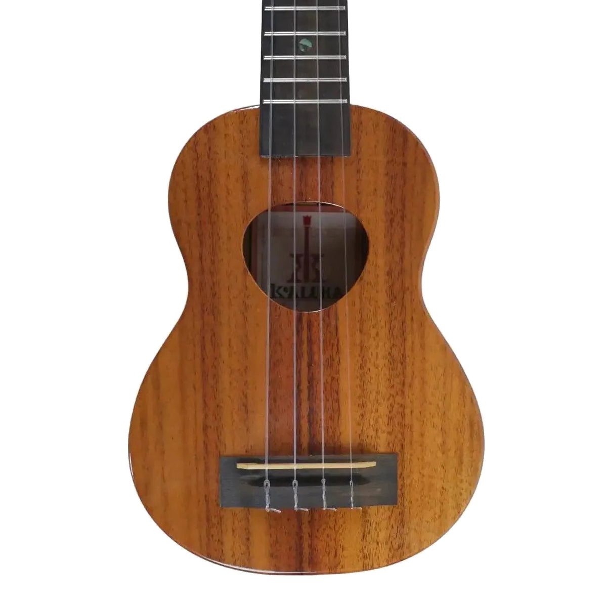 Example photo: body front of an earlier KoAloha KSM-00 gloss solid Hawaiian koa soprano ukulele, showing the koa top, Musubi soundhole and ebony bridge