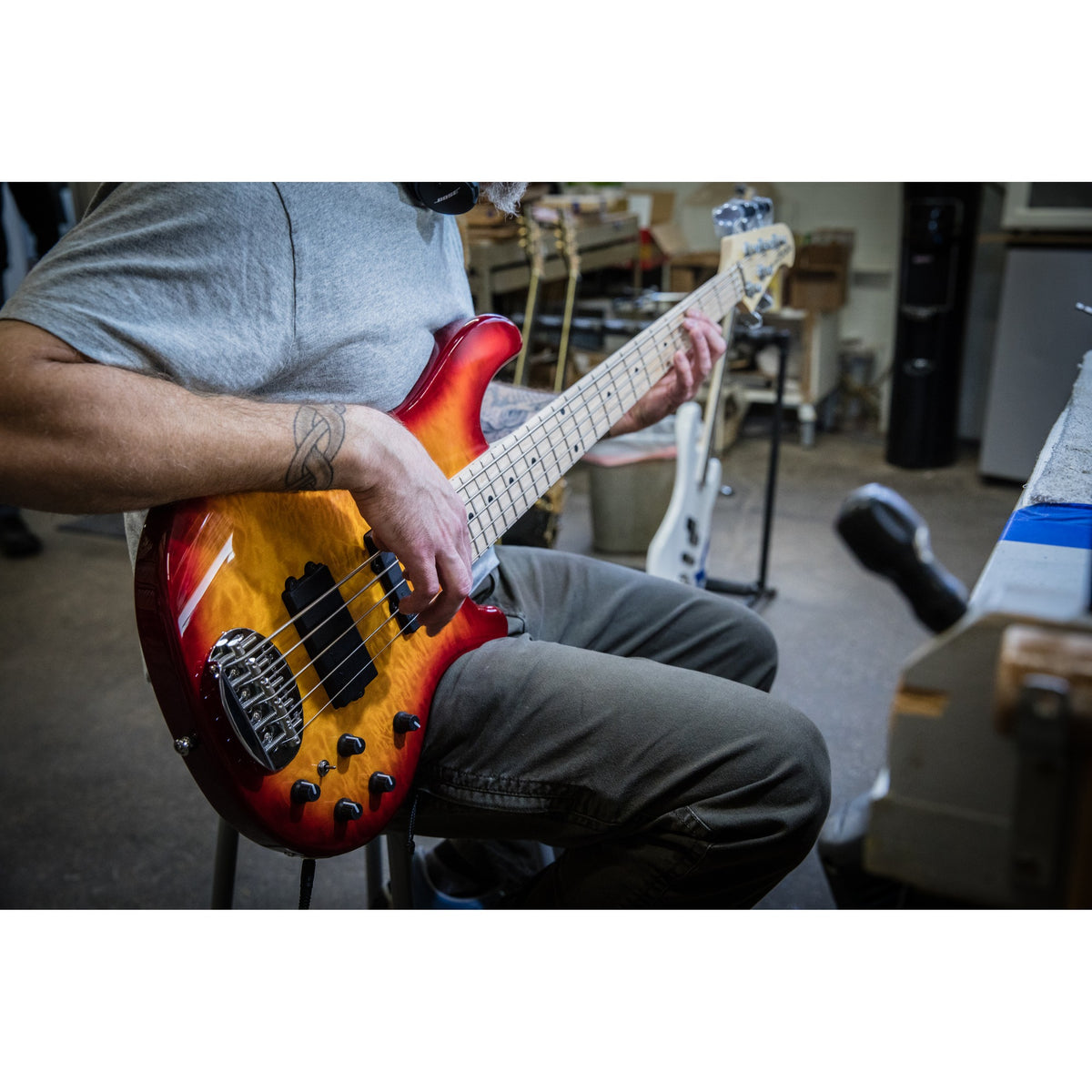 Player holding a Lakland 55-02 Deluxe with a quilted burst top and maple fingerboard in the Lakland shop