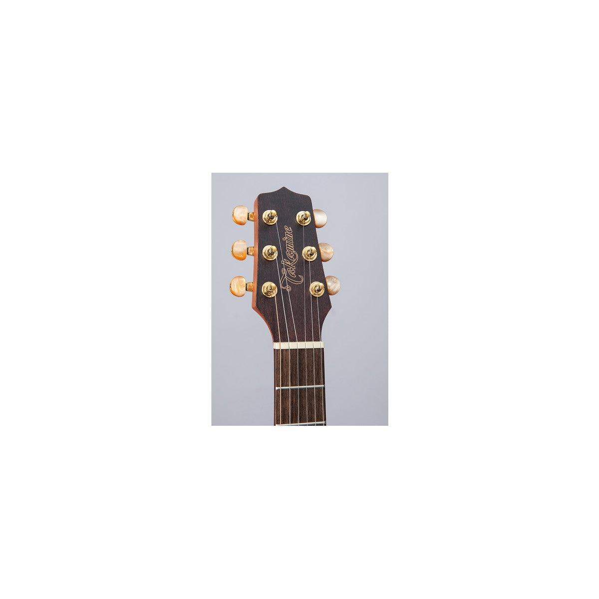Headstock of the Takamine GP3HSE with the Takamine logo and gold tuners with amber pearloid buttons.