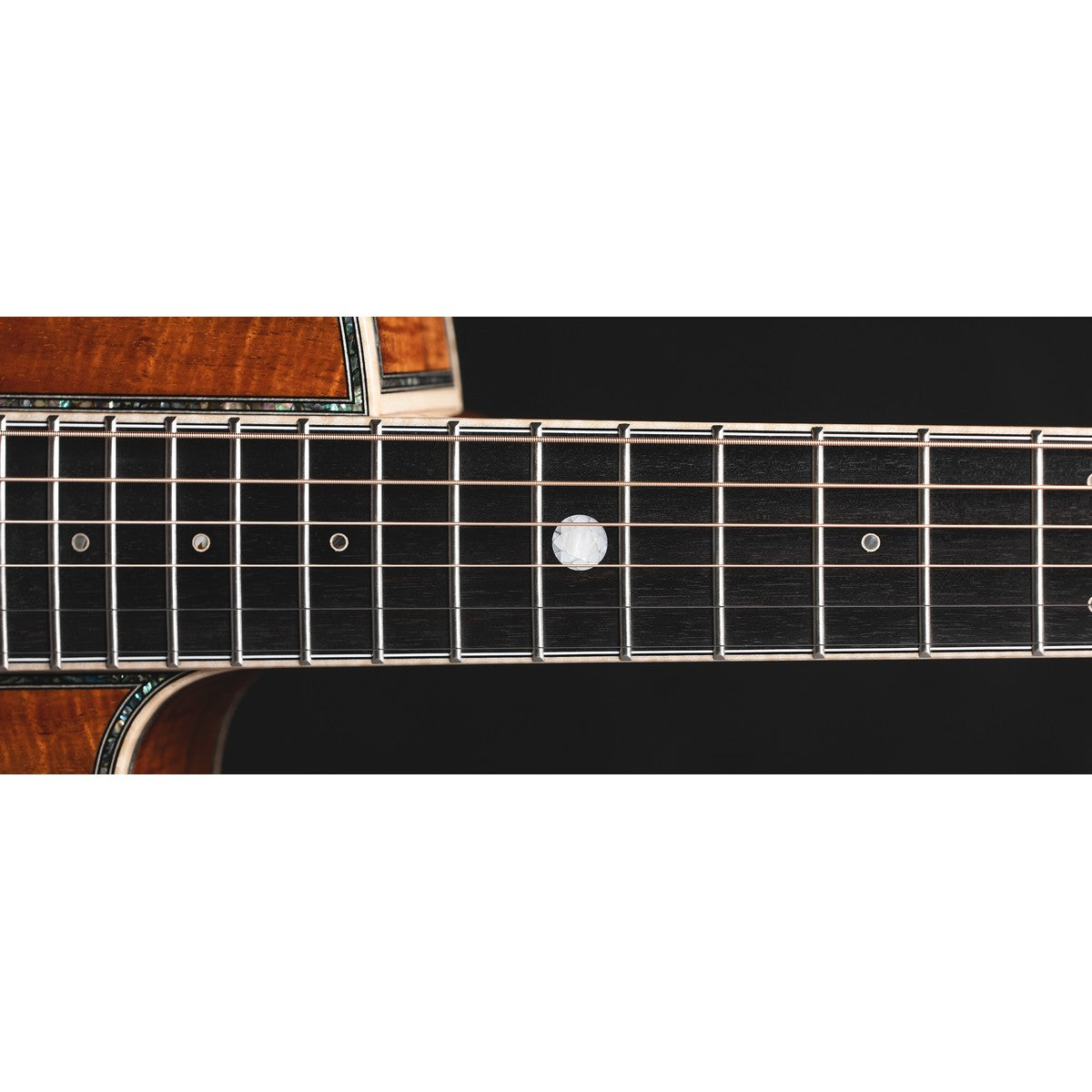 Ebony fingerboard of Takamine THE 60TH with a round diamond-image position marker at the 12th fret and figured Hawaiian koa body at the top.